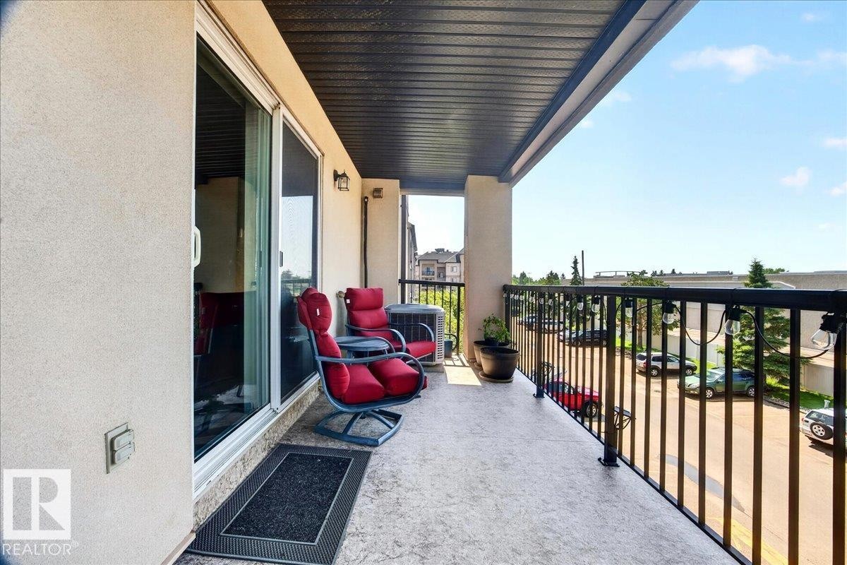 Outdoor balcony featuring a textured concrete floor, black metal railings, and a dark soffit - #306 13111 140 Av Nw, Edmonton, AB - Outdoor With Balcony With Exterior