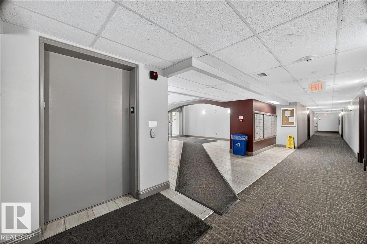 Central elevator access with call buttons features a textured gray door - #306 13111 140 Av Nw, Edmonton, AB - Indoor Photo Showing Other Room