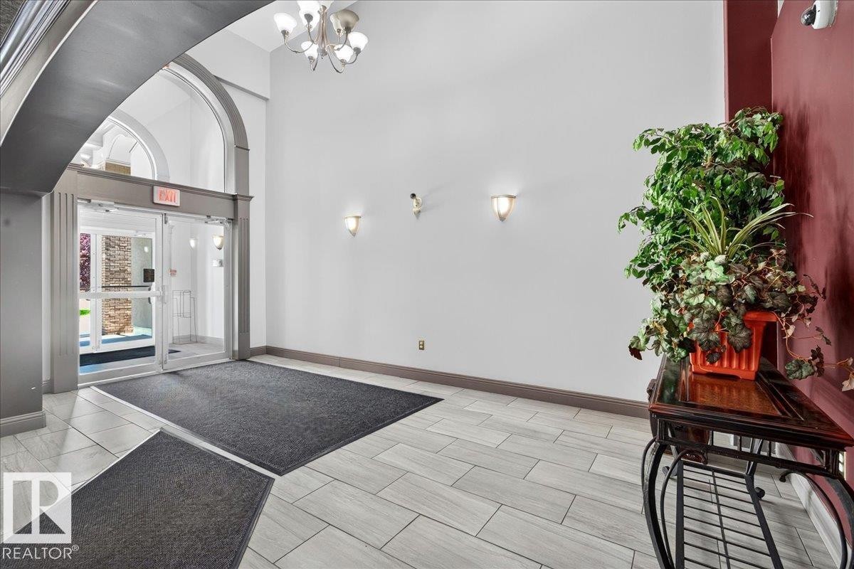 Entryway featuring arched architectural details, light-toned tile flooring, recessed wall sconces, and a contemporary ceiling light fixture - #306 13111 140 Av Nw, Edmonton, AB - Indoor Photo Showing Other Room