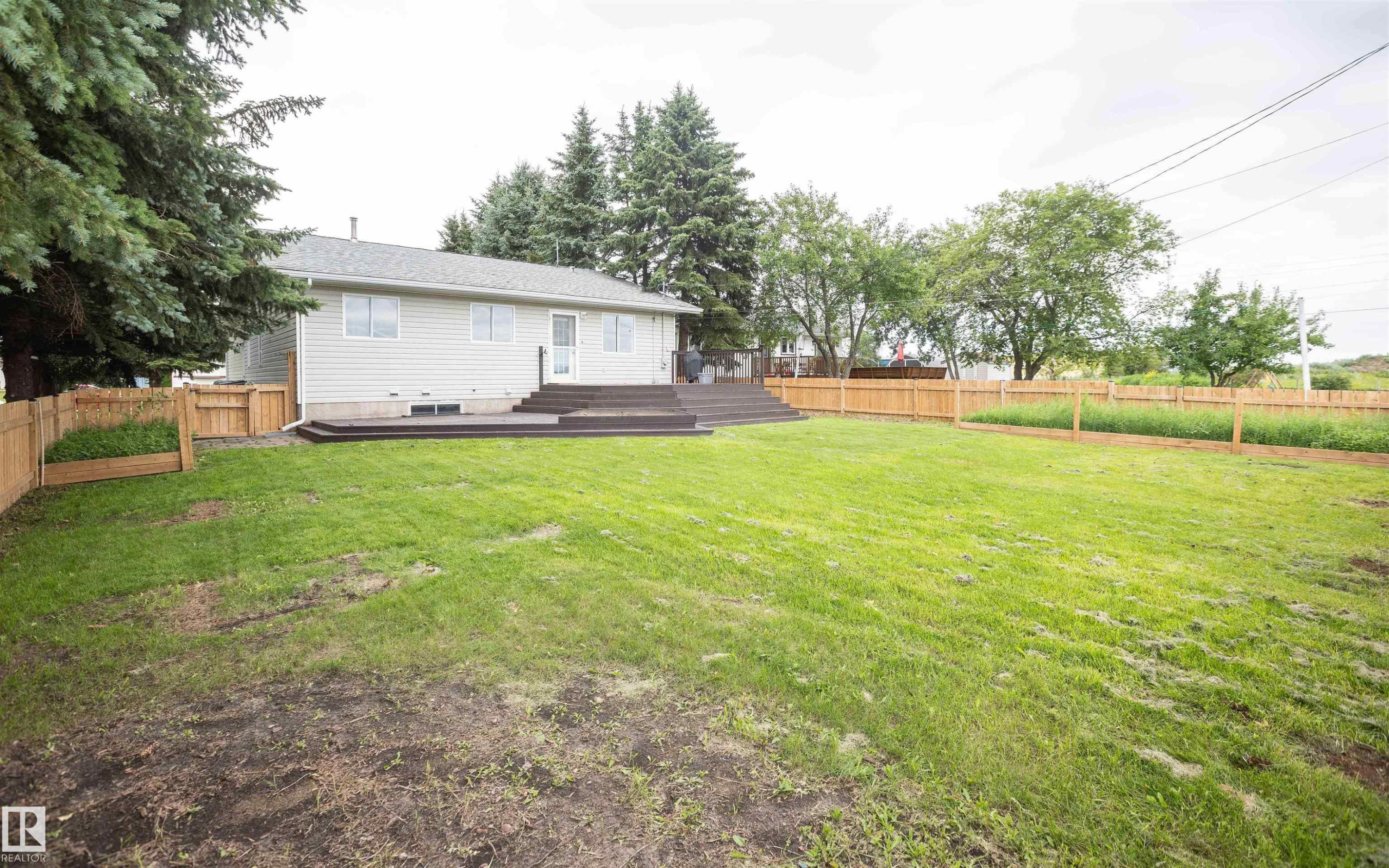 Expansive backyard with a generous lawn and a newly installed wooden privacy fence - 5116 51 Avenue, Pickardville, AB - Outdoor