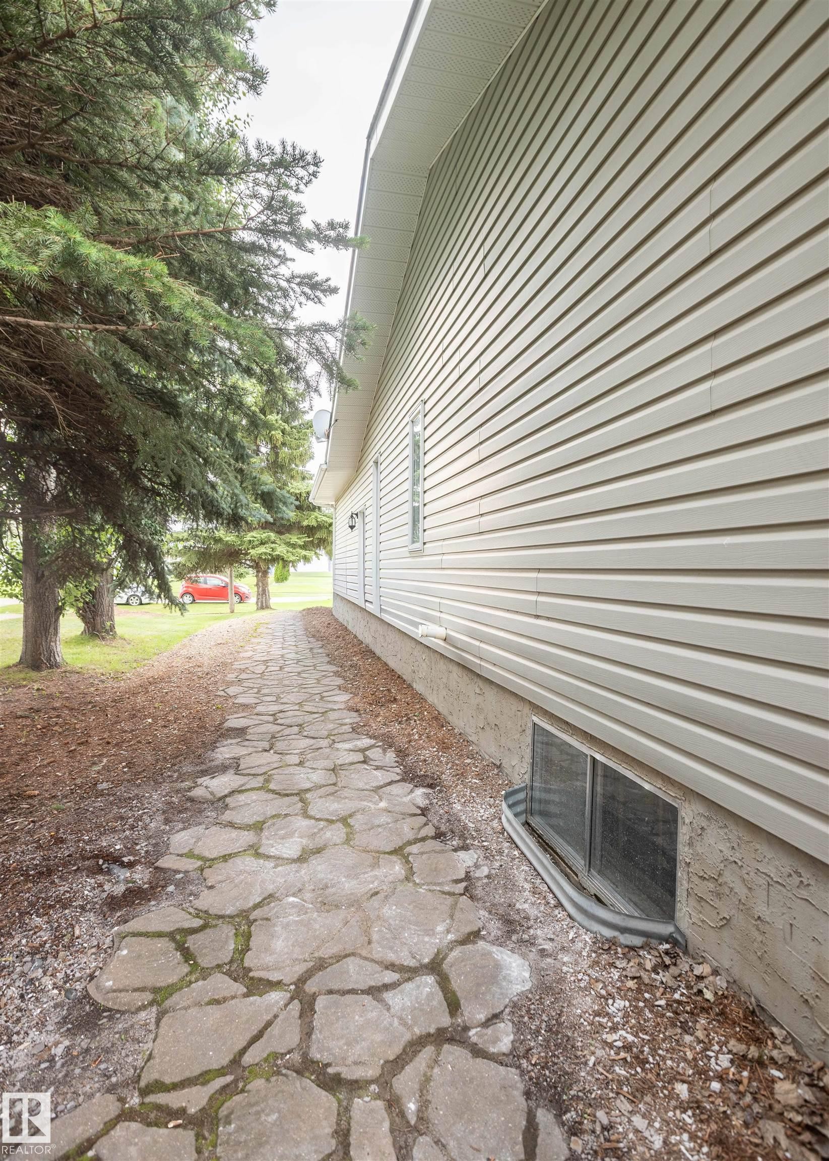 Stone pathway bordering the property, leading past mature trees - 5116 51 Avenue, Pickardville, AB - Outdoor