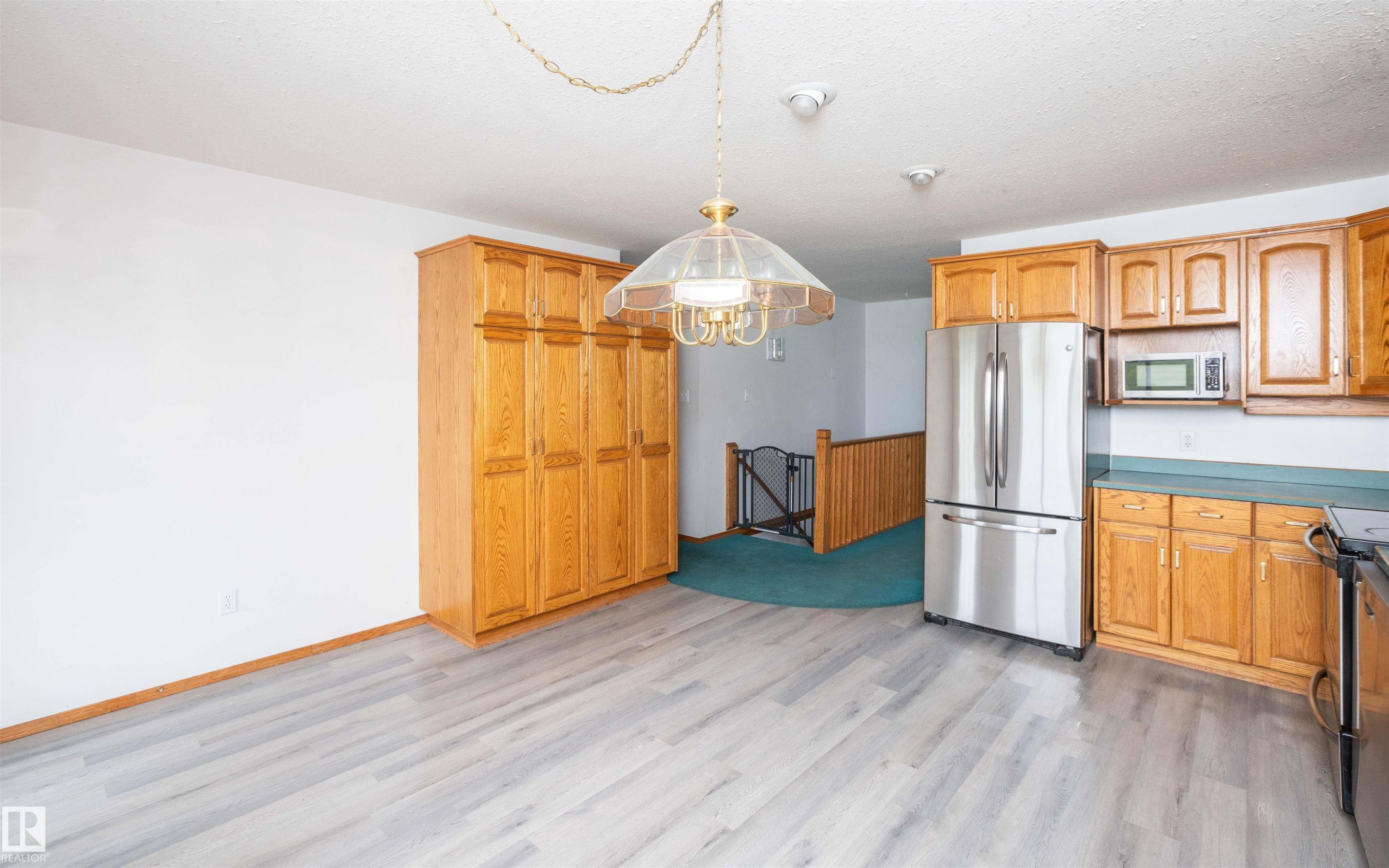 Kitchen and dining area featuring light wood-finish flooring, oak cabinetry, stainless steel refrigerator, and a built-in microwave - 5116 51 Avenue, Pickardville, AB - Indoor Photo Showing Kitchen