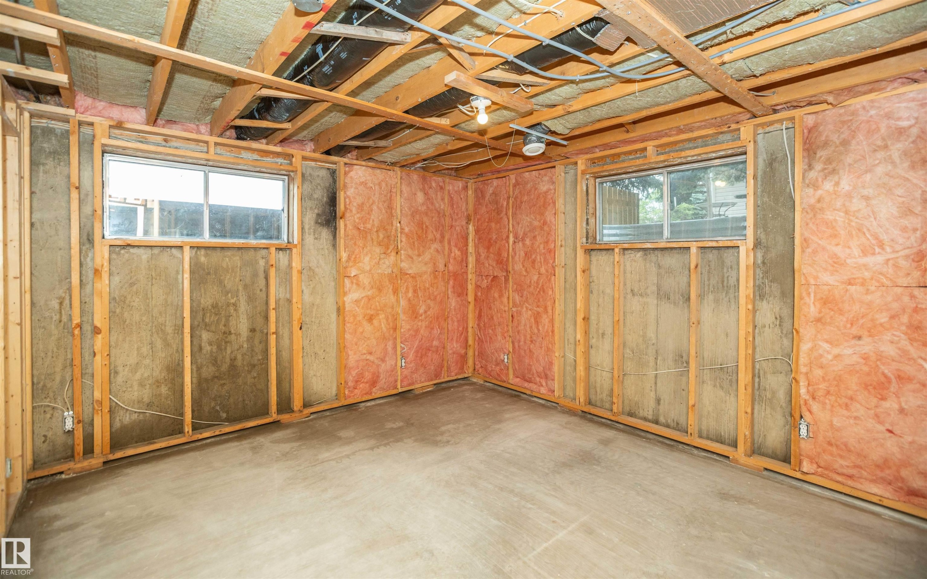 Unfinished basement area featuring exposed wood framing, concrete flooring, two windows, and visible insulation - 5116 51 Avenue, Pickardville, AB - Indoor Photo Showing Other Room