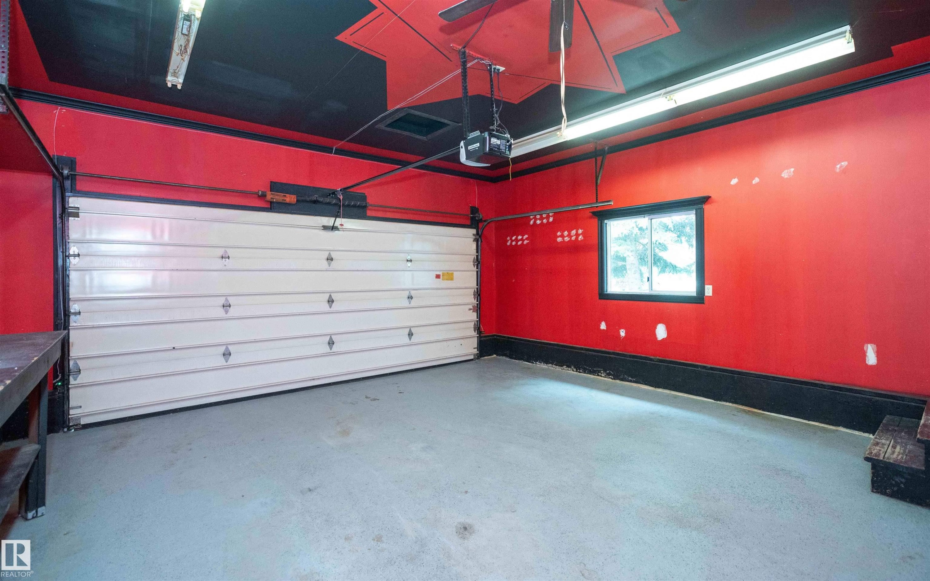 Garage space featuring a paneled overhead door, concrete flooring, and a single window - 5116 51 Avenue, Pickardville, AB - Indoor Photo Showing Garage