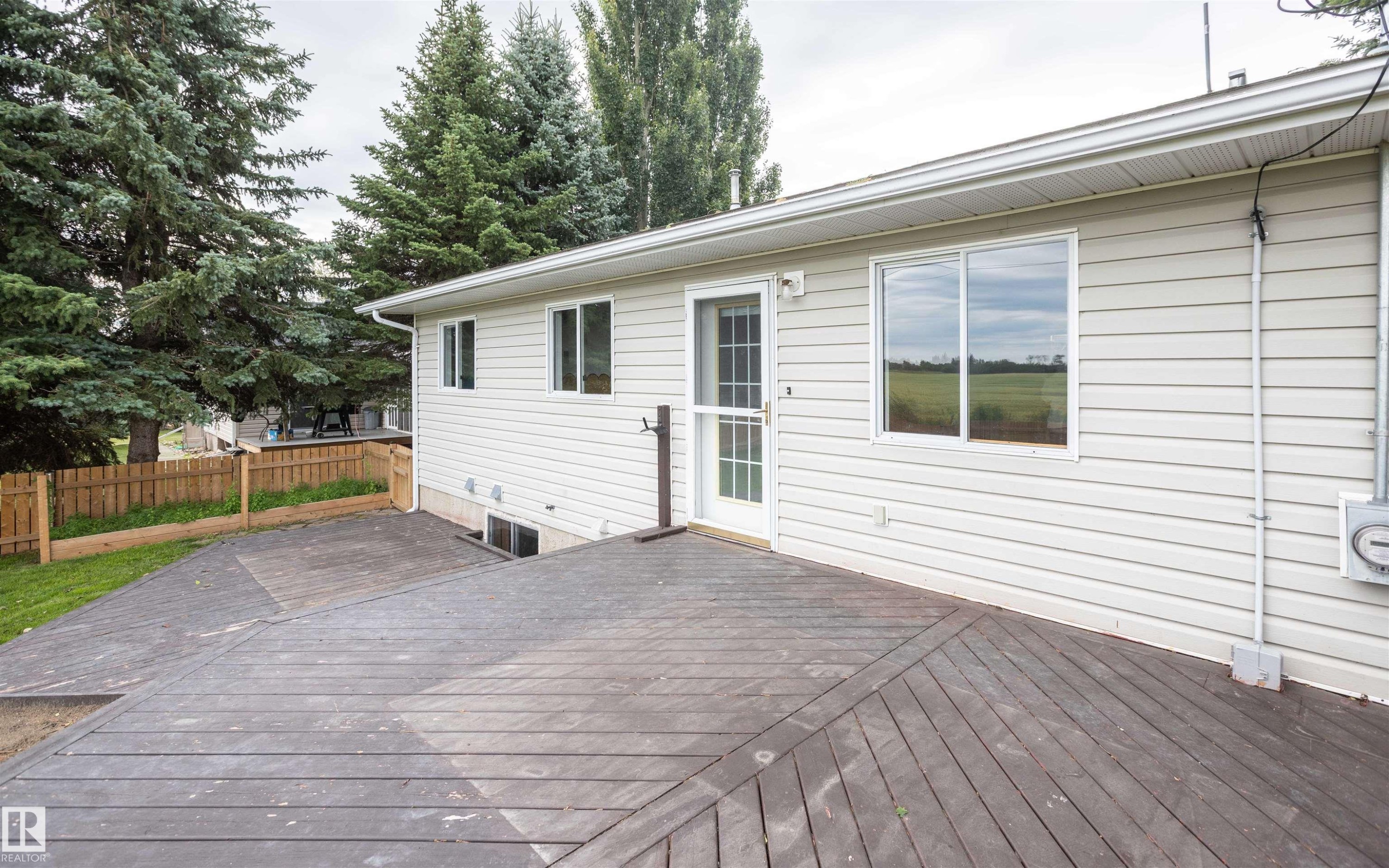 Exterior siding featuring multiple windows, a rear entry door, and an expansive composite deck - 5116 51 Avenue, Pickardville, AB - Outdoor With Deck Patio Veranda With Exterior