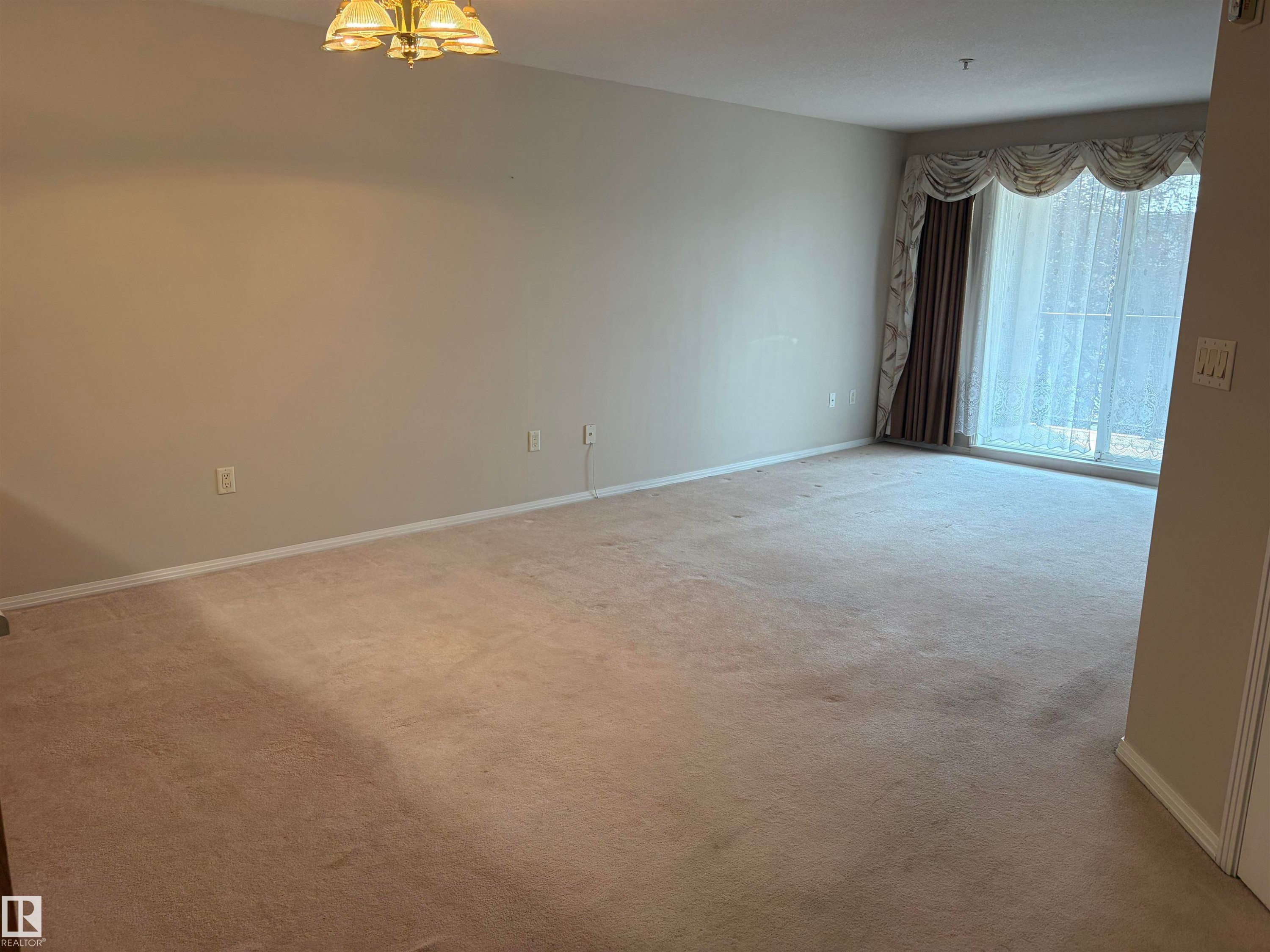 Spacious room with neutral wall tones and beige carpeting - #209 8912 156 St Nw, Edmonton, AB - Indoor Photo Showing Other Room