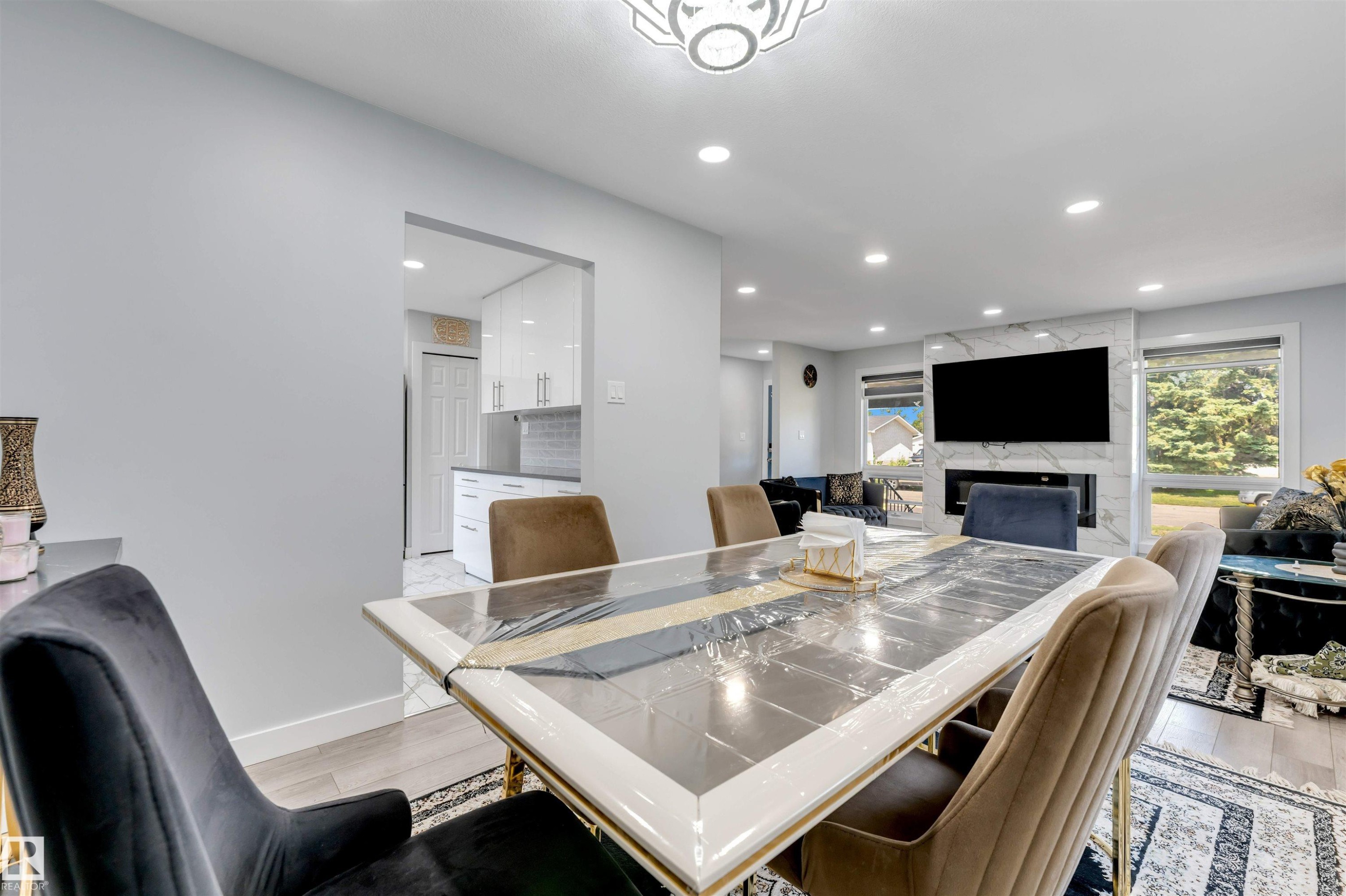 Open-concept dining area with wood-finish flooring, recessed lighting, and a modern chandelier - 7419 33 Avenue Nw, Edmonton, AB - Indoor Photo Showing Dining Room With Fireplace