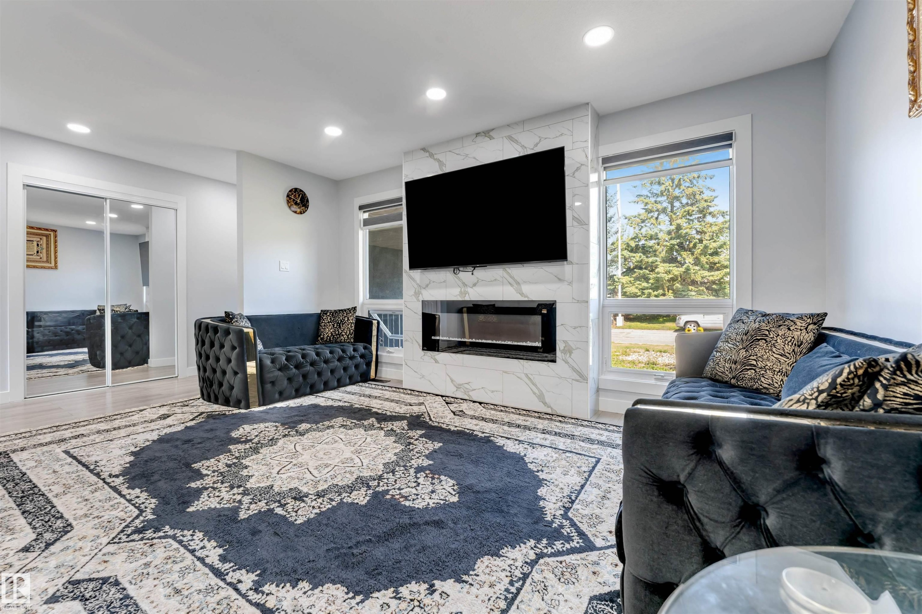 Living area featuring a floor-to-ceiling fireplace with a marble-finish surround and an integrated electric firebox - 7419 33 Avenue Nw, Edmonton, AB - Indoor Photo Showing Living Room With Fireplace