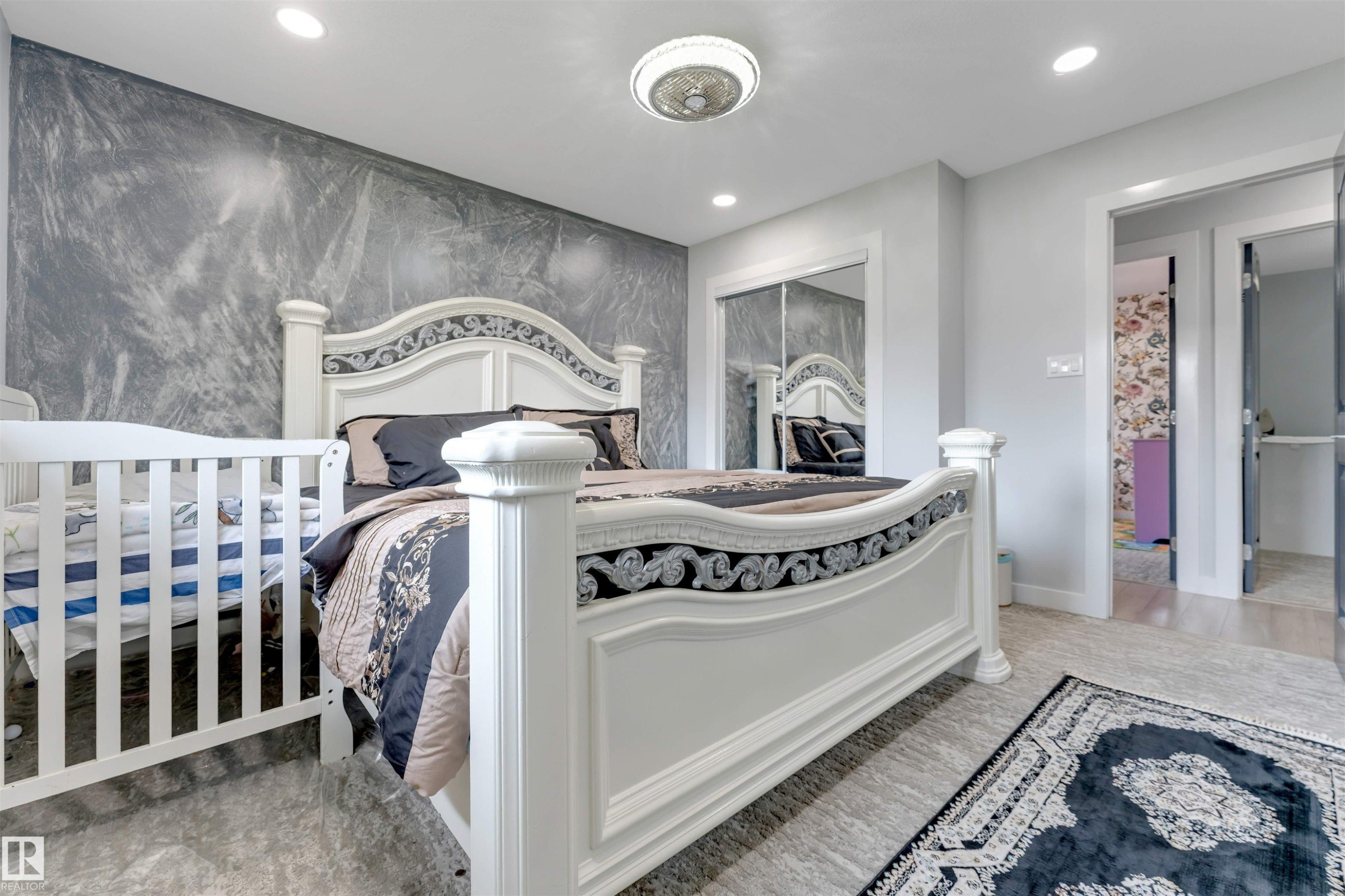 Bedroom featuring a textured accent wall, recessed lighting, a ceiling fan with light, mirrored closet doors, and light-colored flooring - 7419 33 Avenue Nw, Edmonton, AB - Indoor