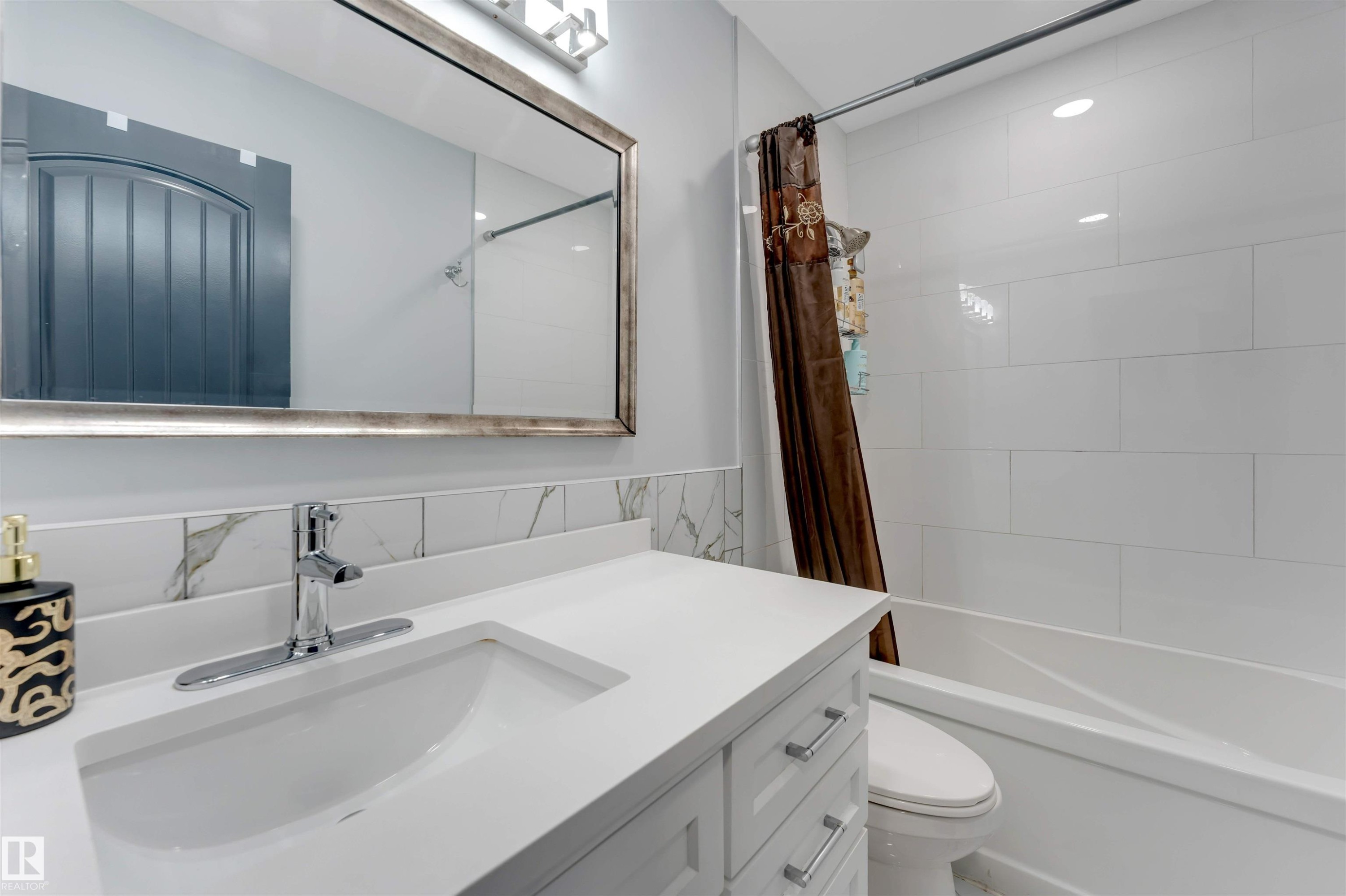 Bathroom vanity featuring a polished chrome faucet, white countertop, and integrated sink - 7419 33 Avenue Nw, Edmonton, AB - Indoor Photo Showing Bathroom