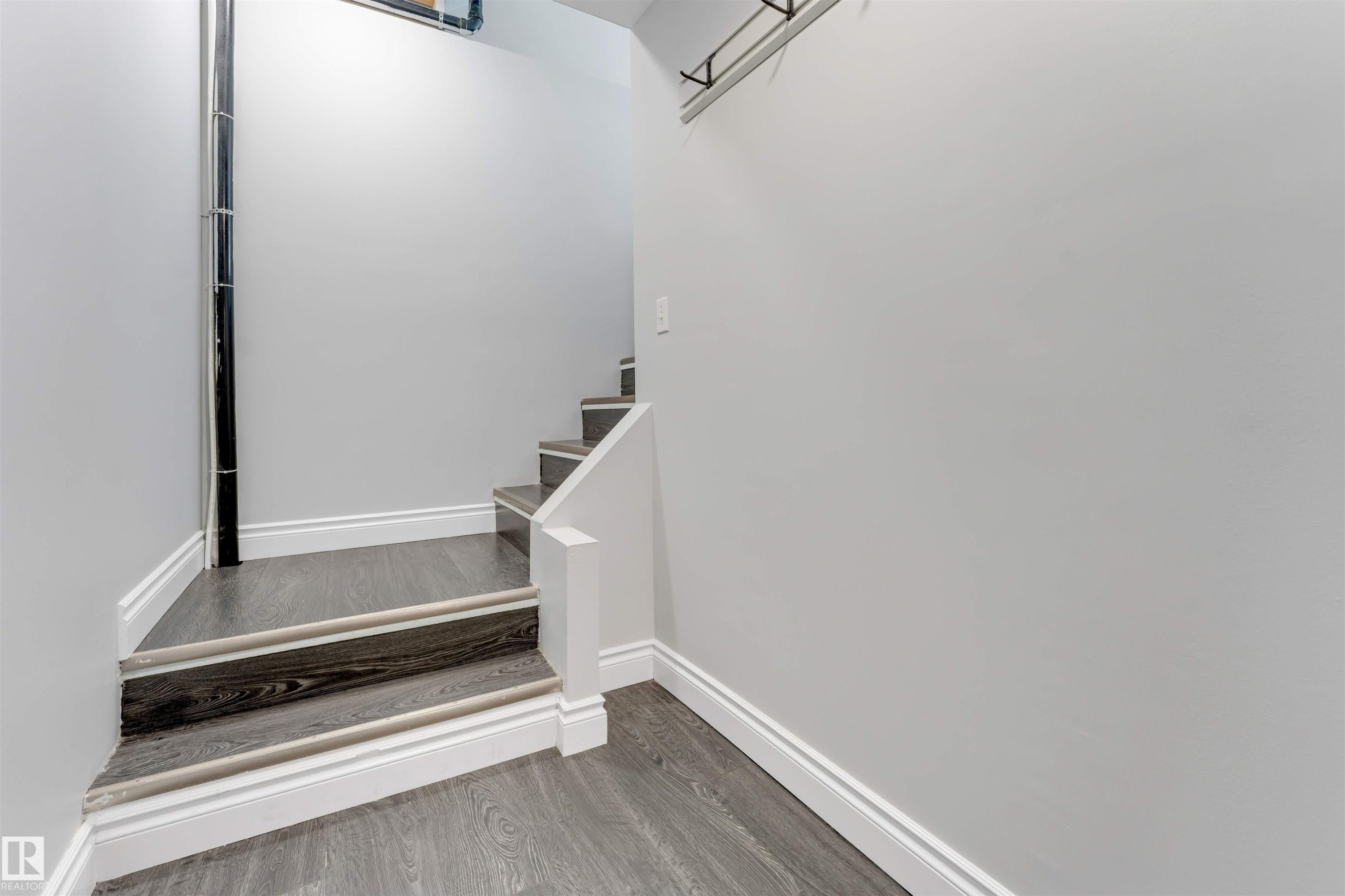Staircase featuring dark wood-finish treads with light-toned nosing, white risers, and a partial white railing - 7419 33 Avenue Nw, Edmonton, AB - Indoor Photo Showing Other Room
