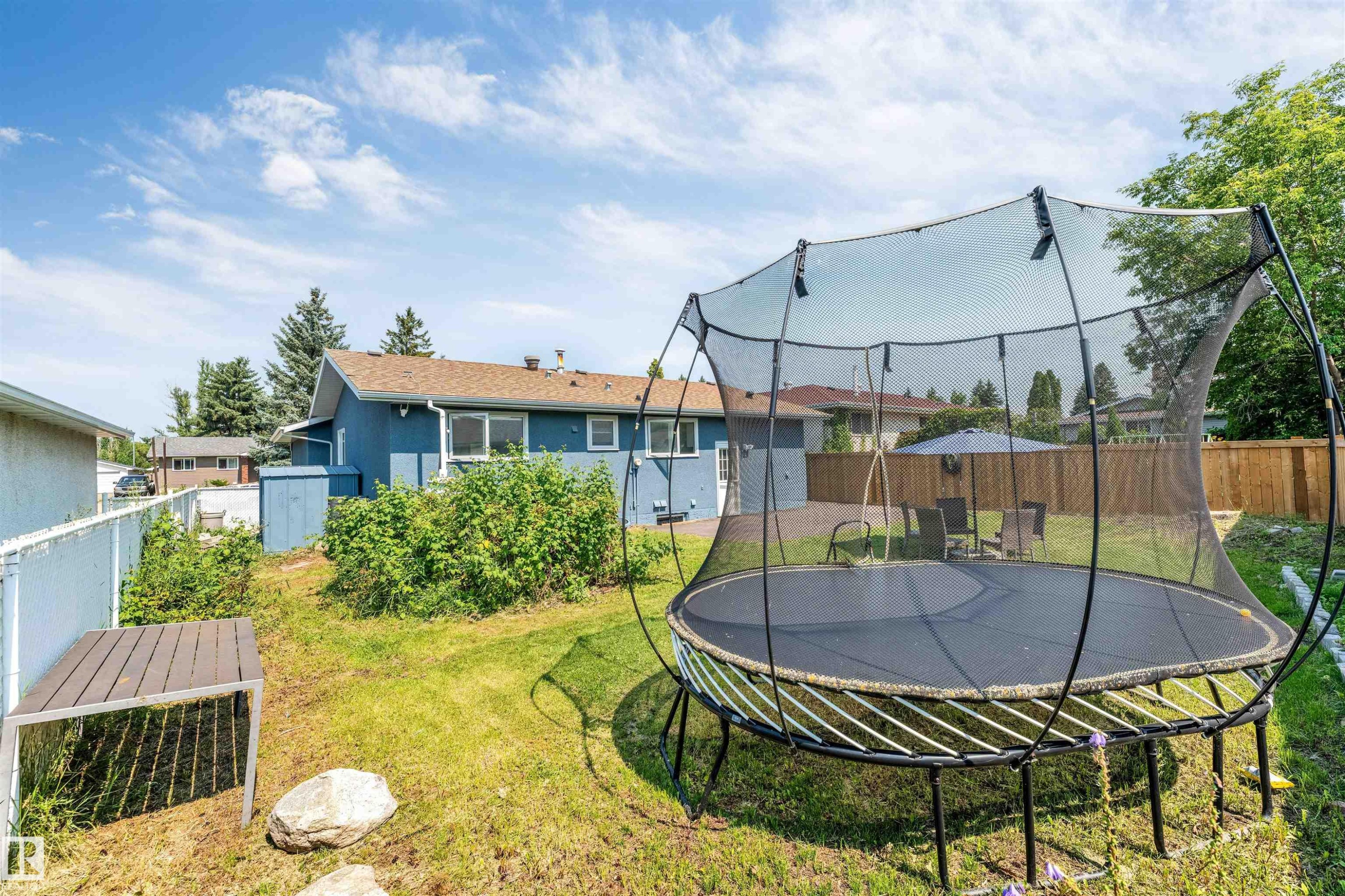 Expansive backyard featuring a partial privacy fence, mature trees, and a visible exterior of the property - 7419 33 Avenue Nw, Edmonton, AB - Outdoor