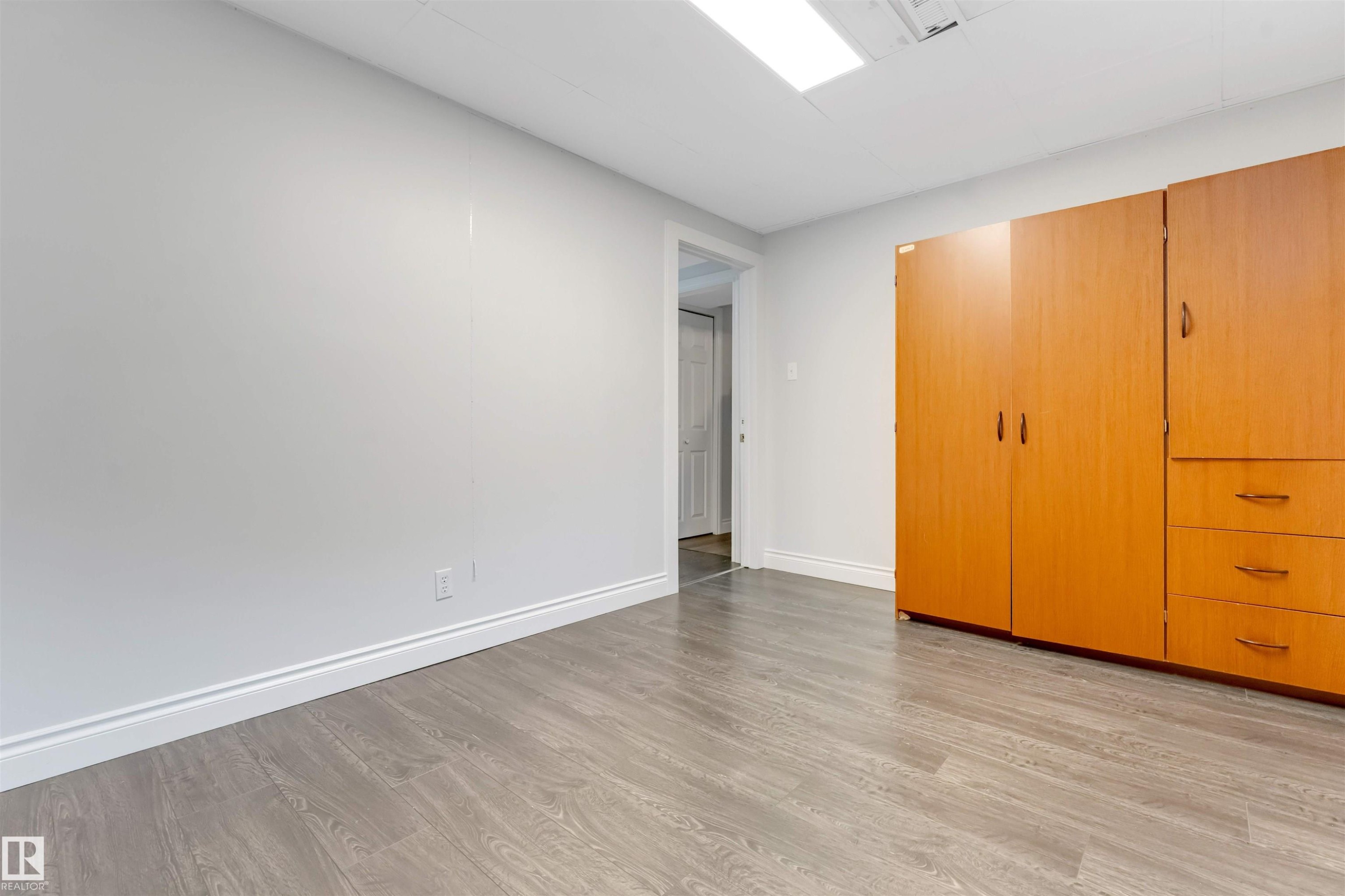 Room featuring wood-finish flooring, light grey walls, and white baseboards - 7419 33 Avenue Nw, Edmonton, AB - Indoor Photo Showing Other Room