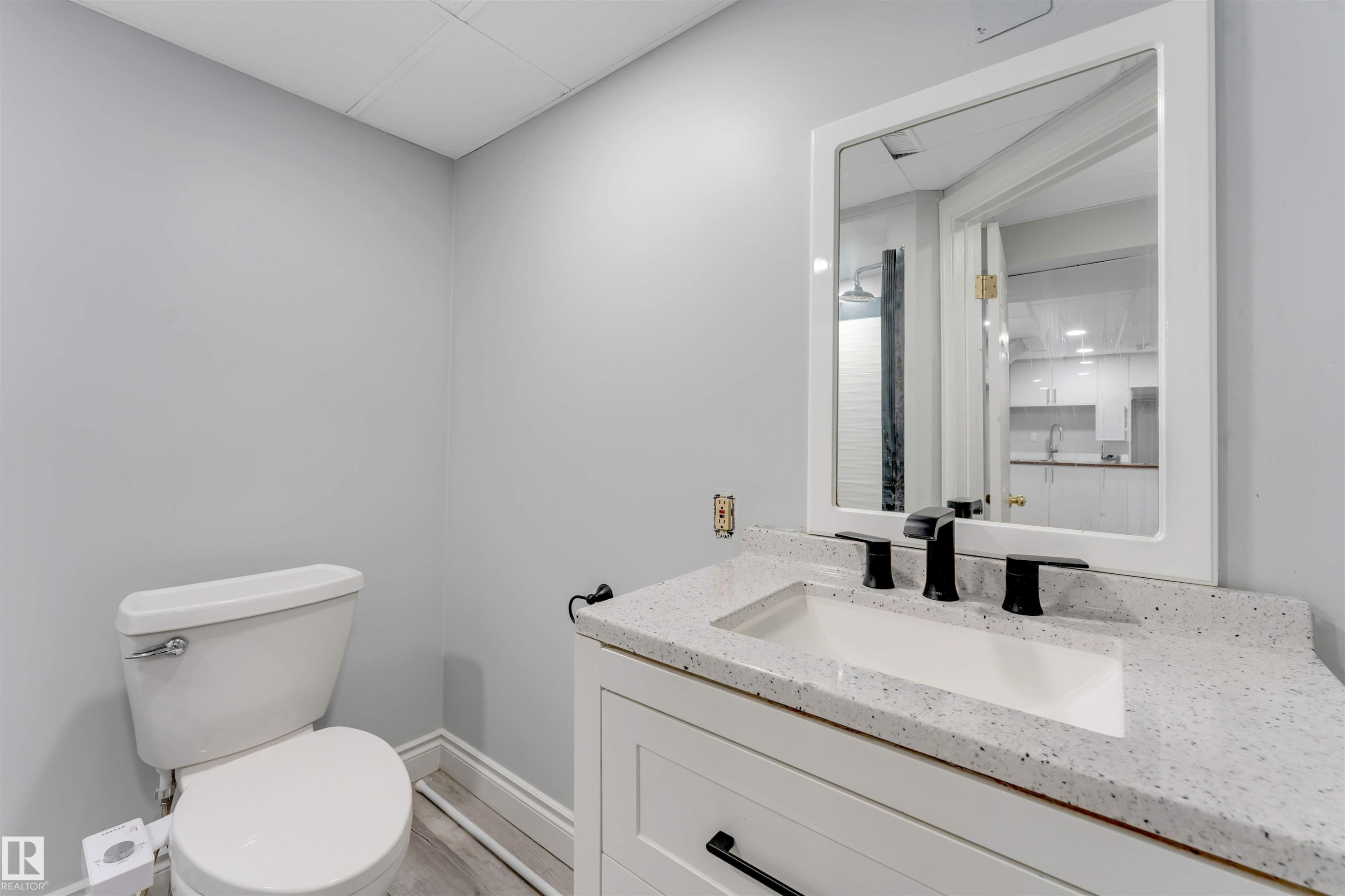 Bathroom featuring a white vanity with a speckled countertop, integrated sink, and matte black faucet - 7419 33 Avenue Nw, Edmonton, AB - Indoor Photo Showing Bathroom