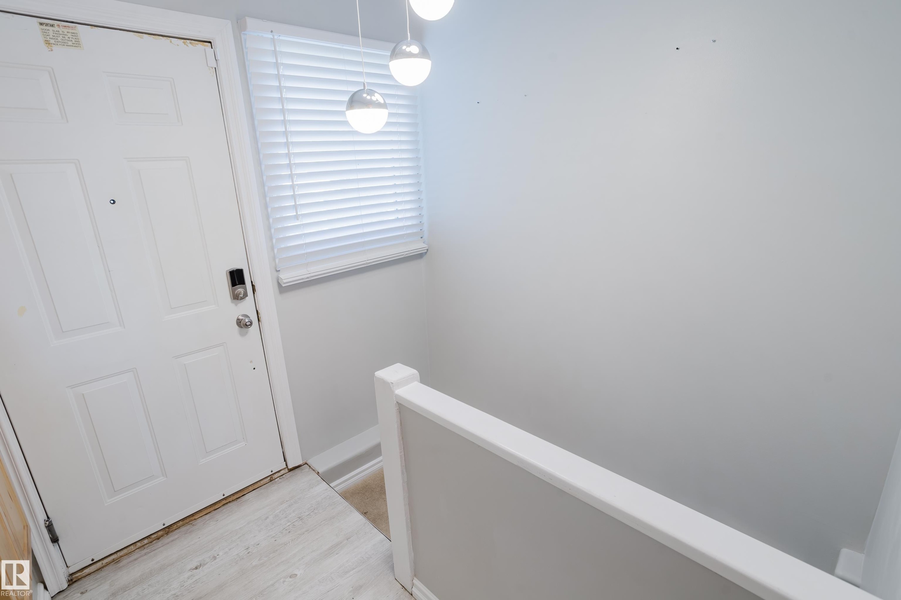 Entryway featuring a paneled door, wood-finish flooring, and a contemporary pendant light fixture - 12431 81 Street Nw, Edmonton, AB - Indoor Photo Showing Other Room