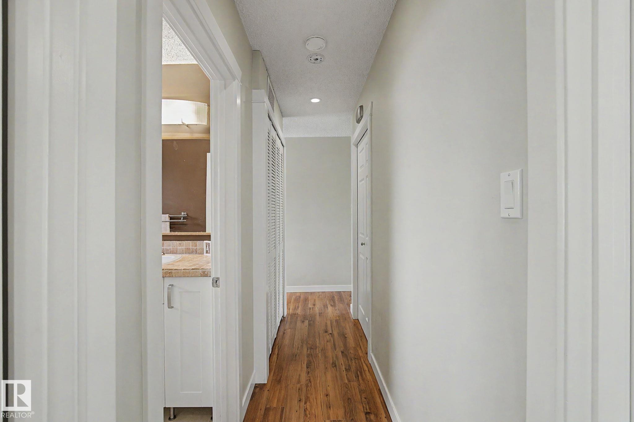 Hallway featuring wood-finish flooring, recessed lighting, and crisp white trim - 8823 130A Avenue Nw, Edmonton, AB - Indoor Photo Showing Other Room