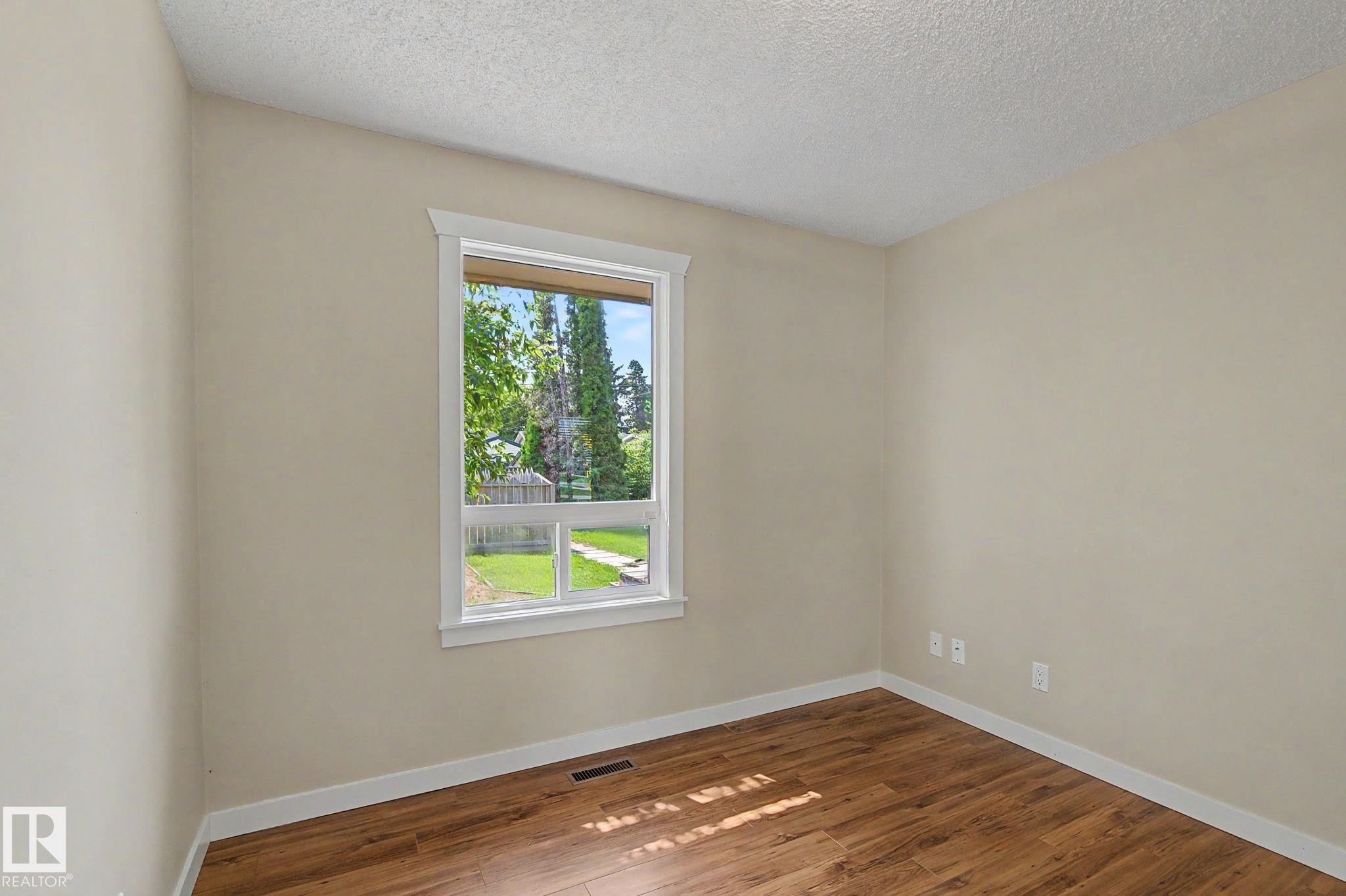Room featuring a white-trimmed window, wood-finish flooring, and light-toned walls - 8823 130A Avenue Nw, Edmonton, AB - Indoor Photo Showing Other Room