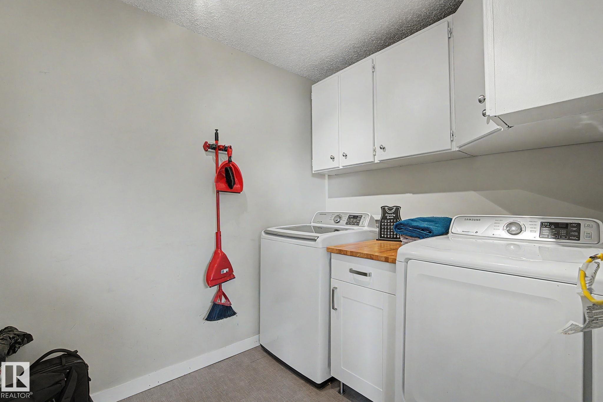 Dedicated laundry space featuring white upper cabinetry, a wood-finish countertop, and base cabinetry with a drawer - 8823 130A Avenue Nw, Edmonton, AB - Indoor Photo Showing Laundry Room