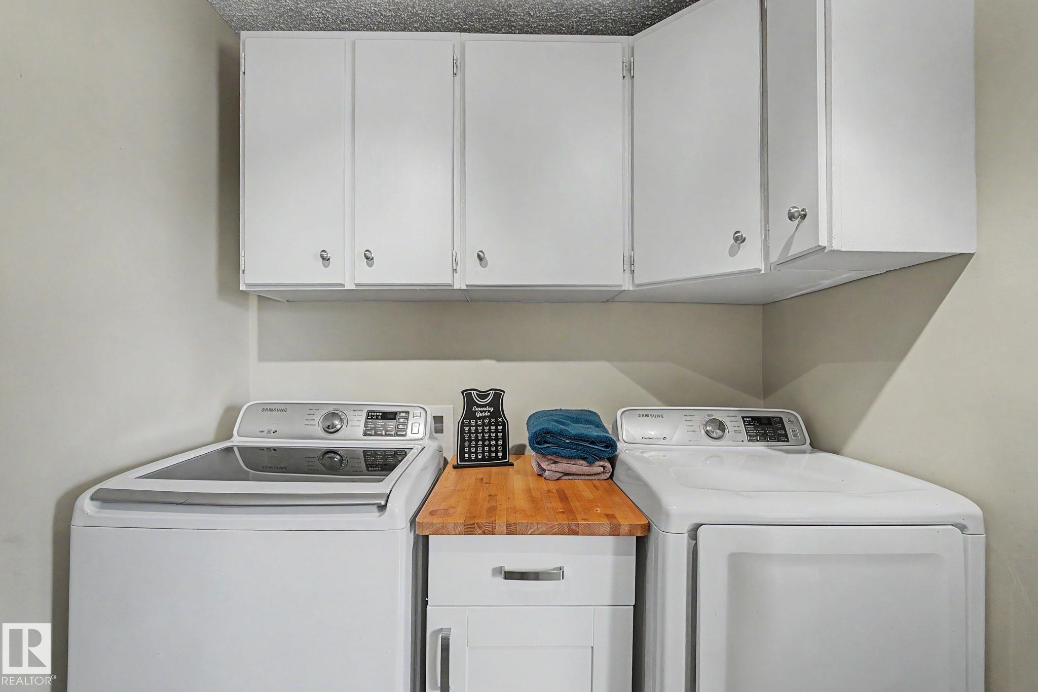 Laundry area featuring white cabinetry, a wood-finish countertop, and neutral wall paint - 8823 130A Avenue Nw, Edmonton, AB - Indoor Photo Showing Laundry Room