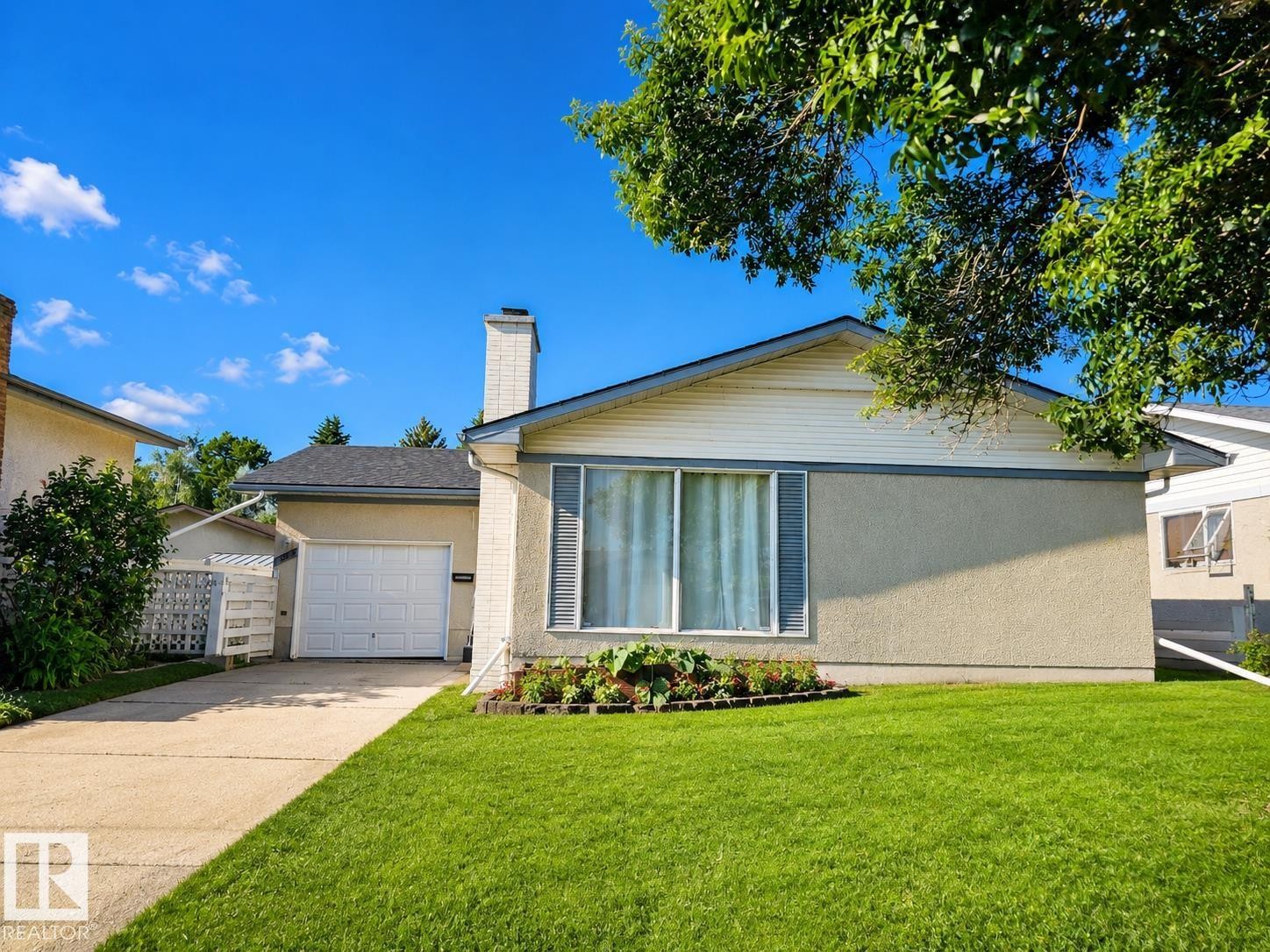 Single-story residence featuring stucco and siding exterior finishes, an attached front window with shutters, and a brick chimney - 7812 144 Avenue Nw, Edmonton, AB - Outdoor