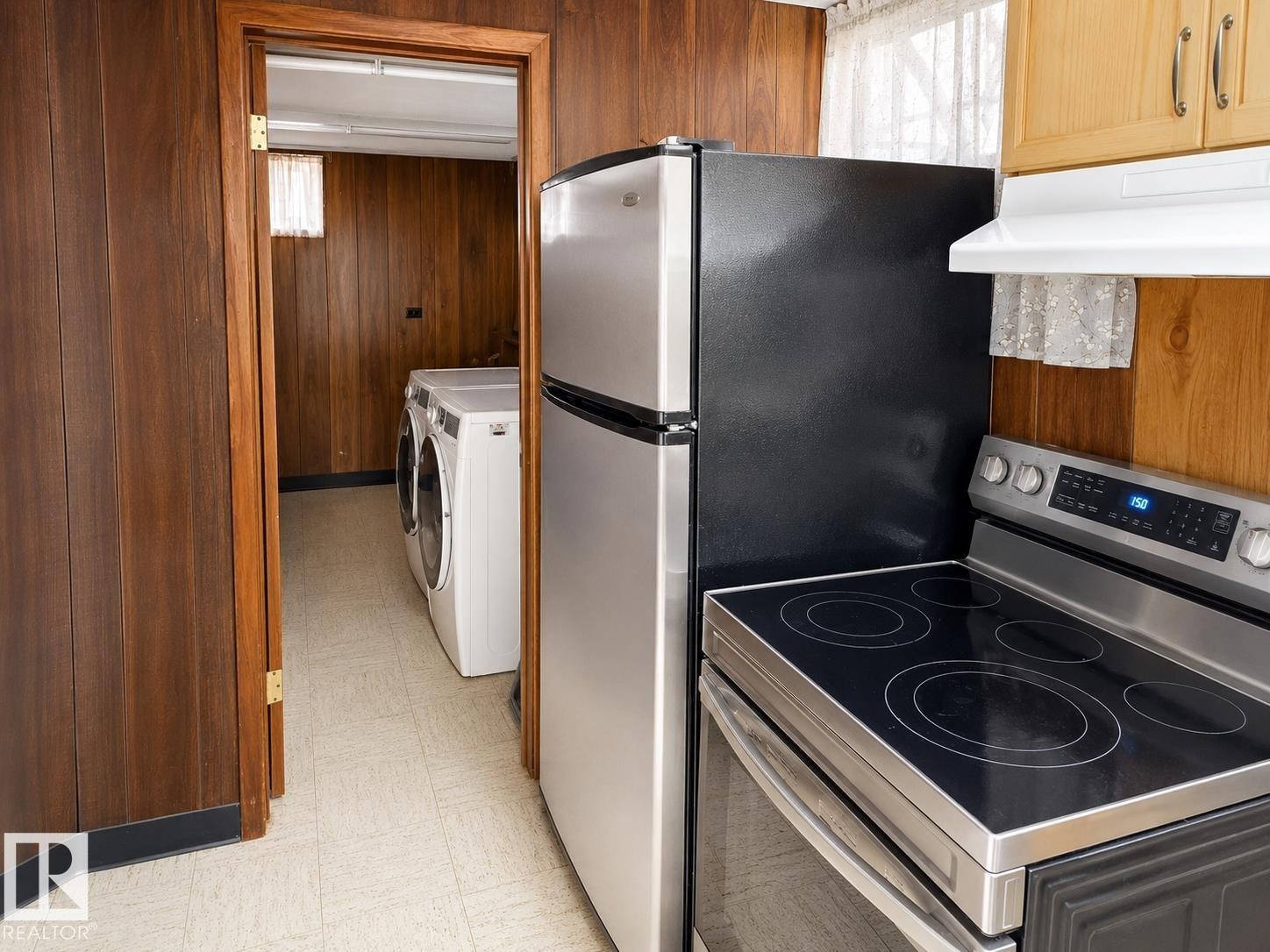 Kitchen area featuring a stainless steel refrigerator and electric range with a glass cooktop - 7812 144 Avenue Nw, Edmonton, AB - Indoor
