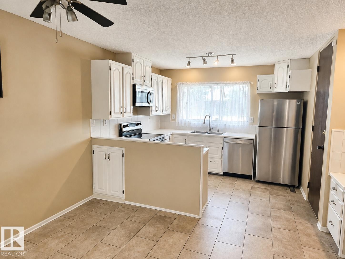Kitchen featuring white cabinetry, tile flooring, stainless steel appliances, white countertops, and a ceiling fan - 7812 144 Avenue Nw, Edmonton, AB - Indoor Photo Showing Kitchen