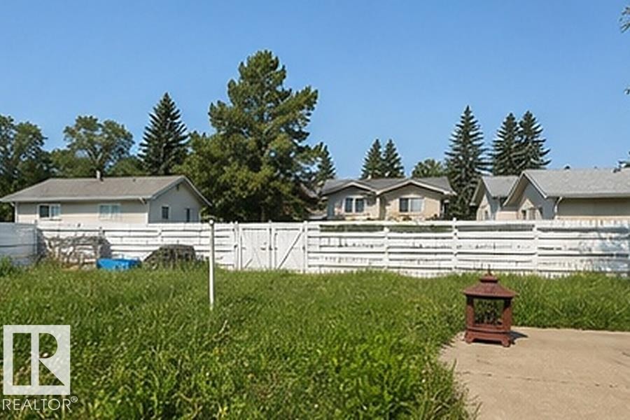 Expansive grassy area featuring a white horizontal plank fence with double gates - 7812 144 Avenue Nw, Edmonton, AB - Outdoor
