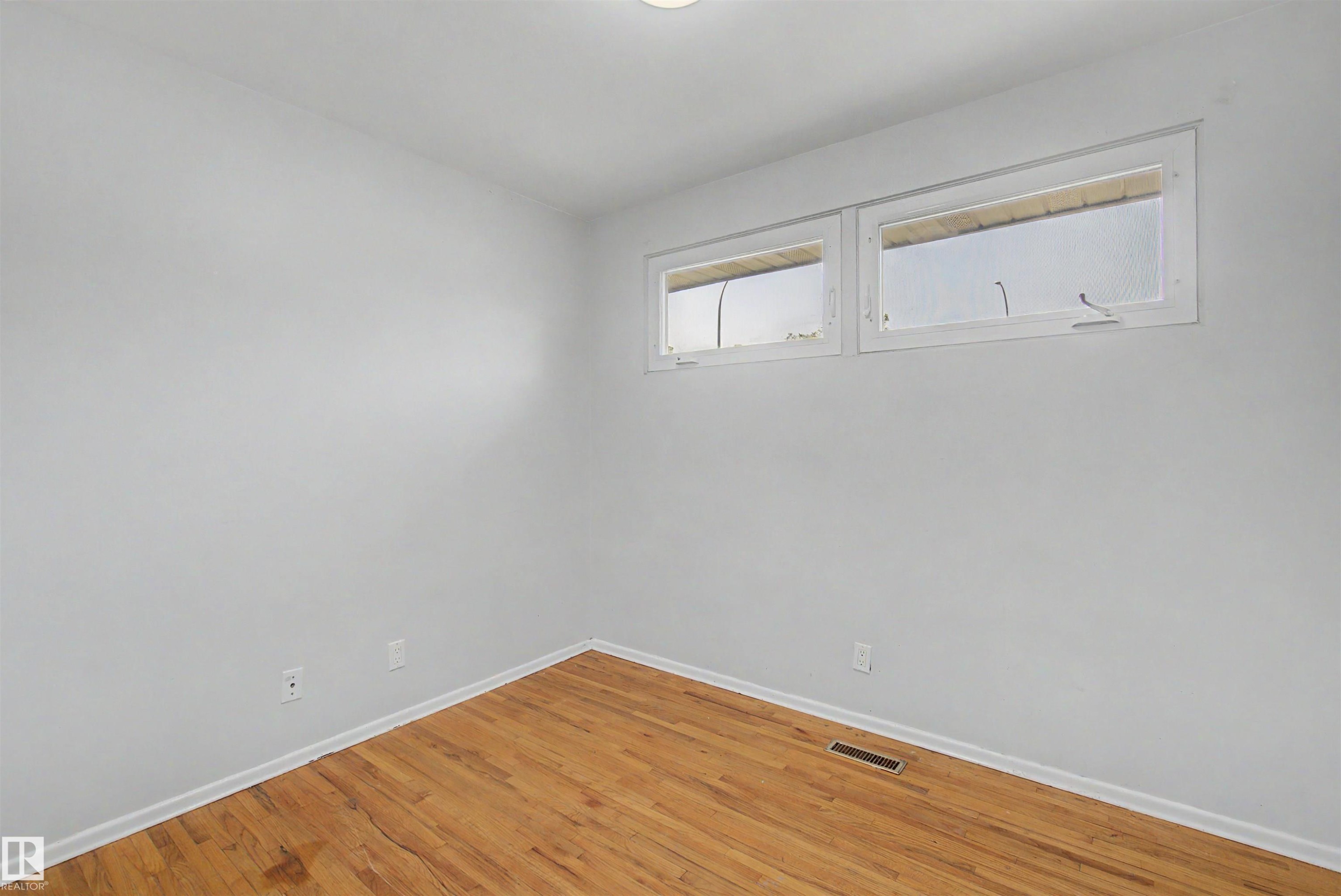 Interior space featuring wood-finish flooring, light gray wall paint, and white trim - 8215 149 Street Nw, Edmonton, AB - Indoor Photo Showing Other Room