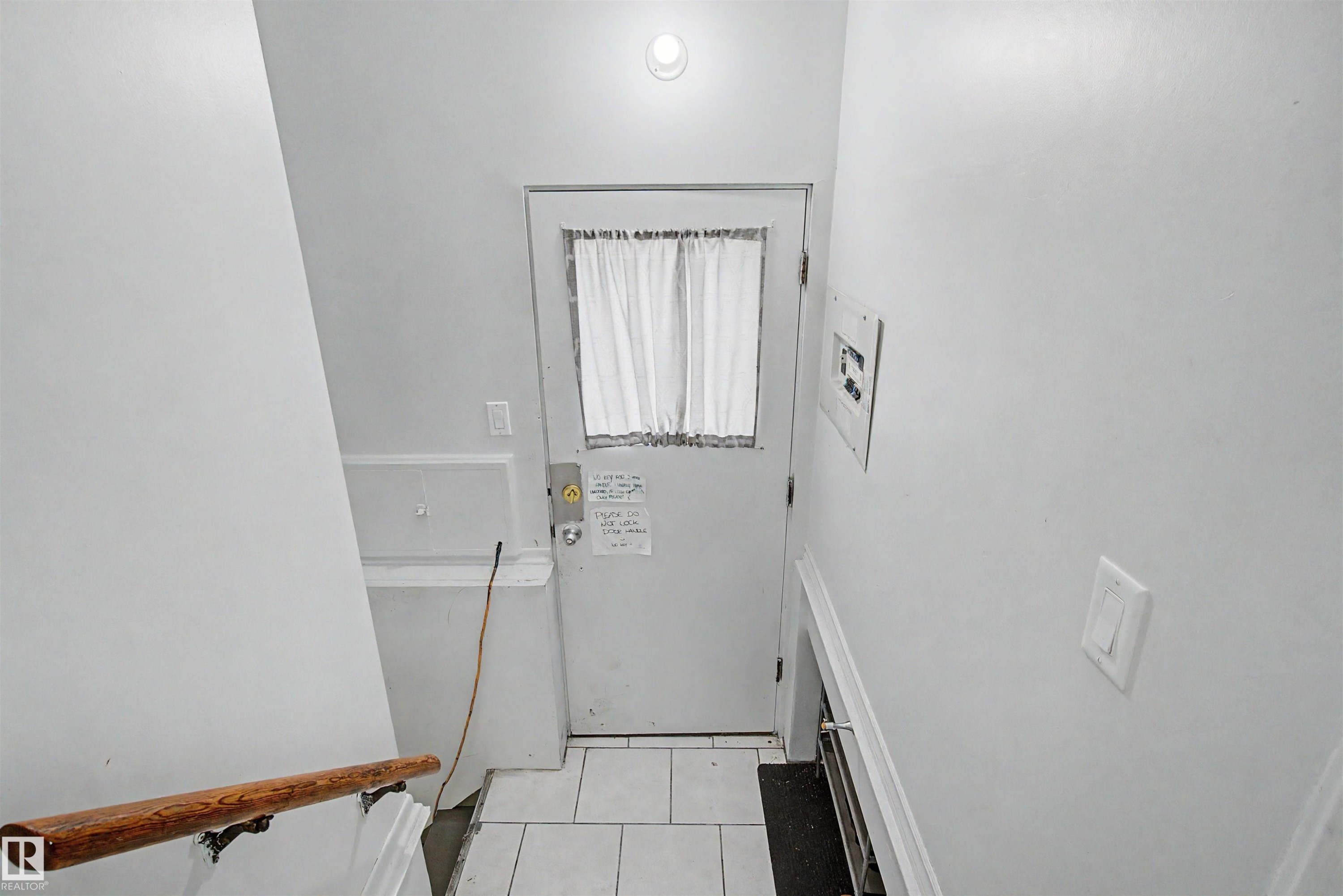 White interior door with a paneled window, featuring a light-colored curtain - 8215 149 Street Nw, Edmonton, AB - Indoor Photo Showing Other Room