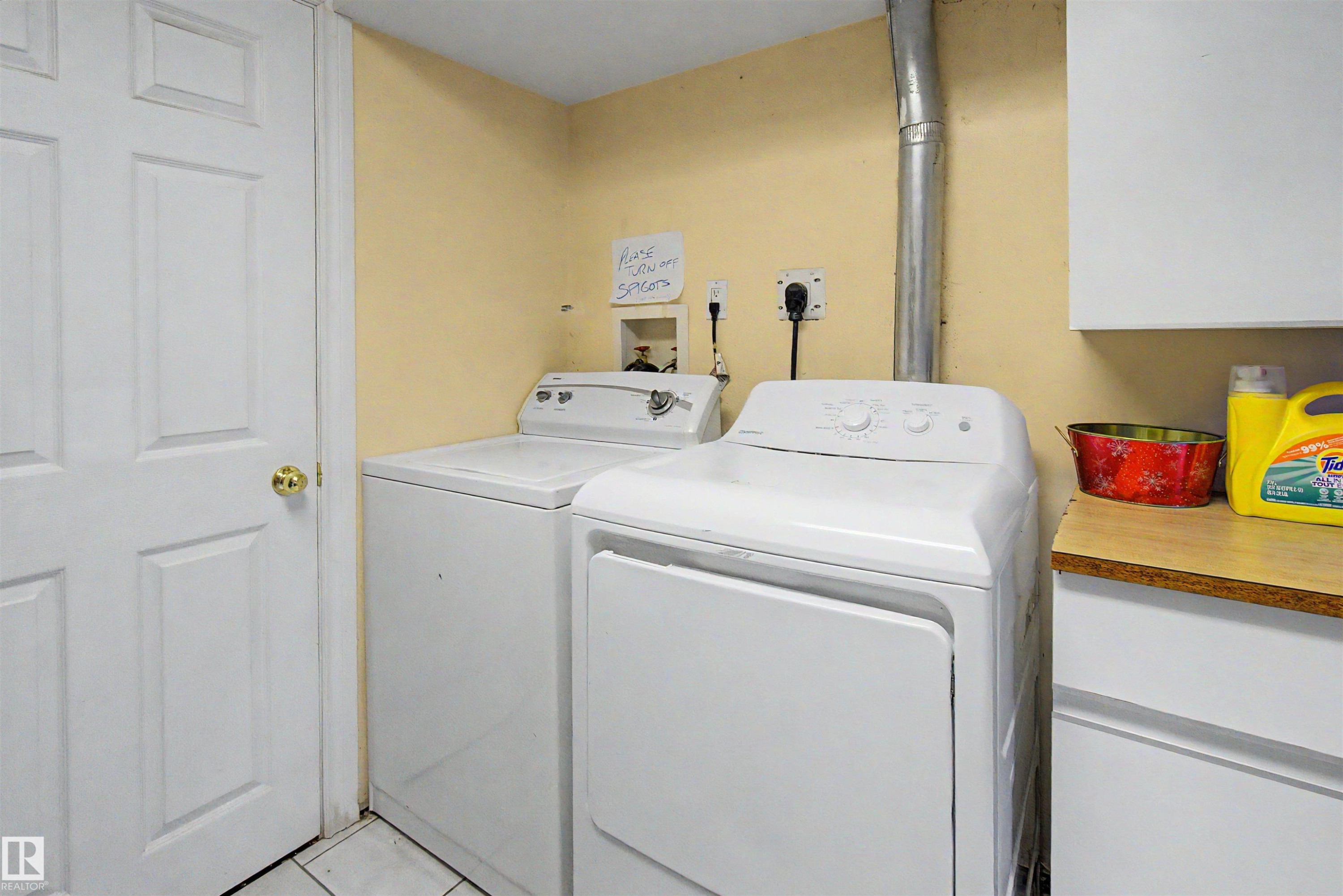 Utility area featuring a white six-panel door with brass hardware, tile flooring, and light-colored walls - 8215 149 Street Nw, Edmonton, AB - Indoor Photo Showing Laundry Room