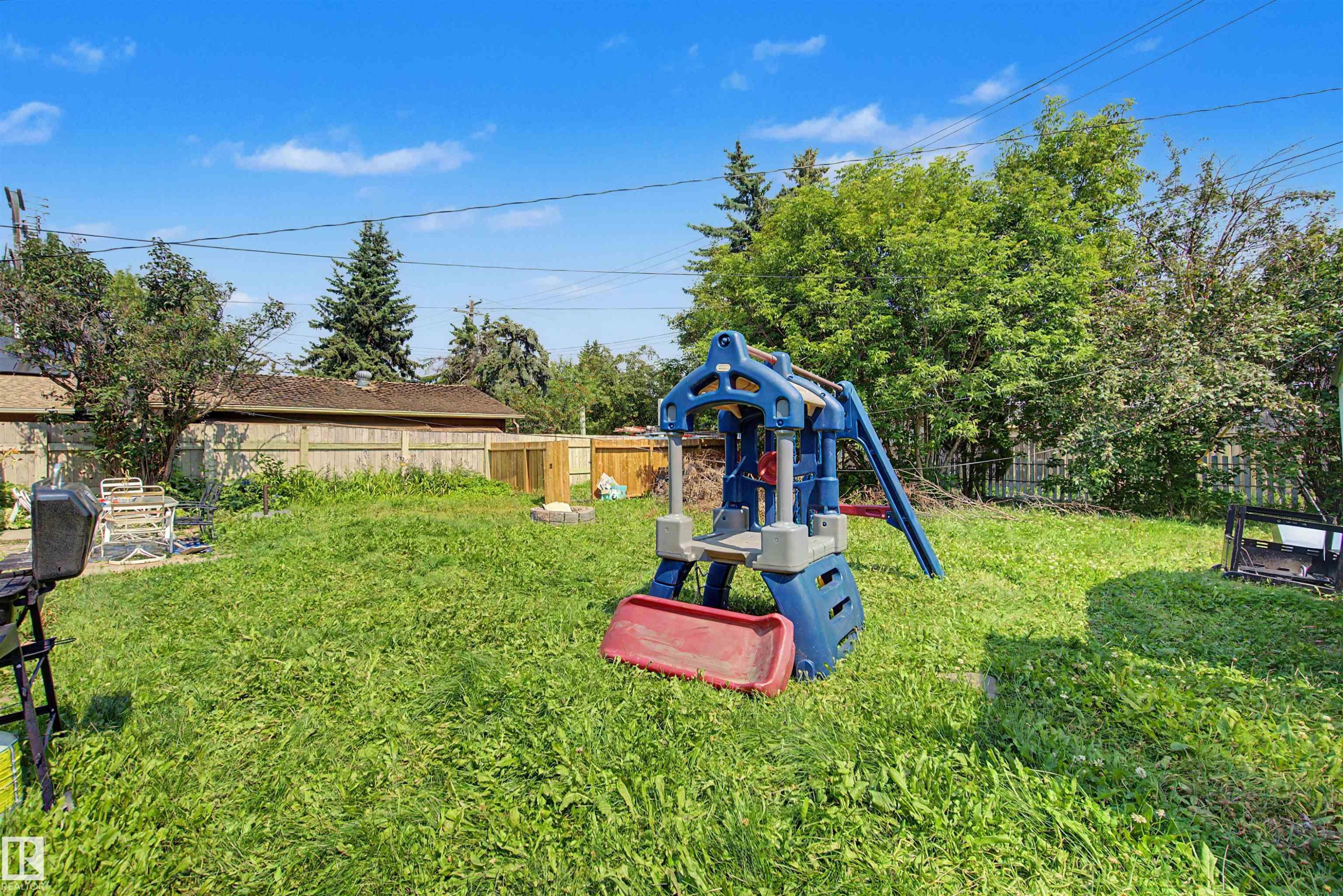 Expansive grassy backyard featuring a perimeter wooden fence and mature trees - 8215 149 Street Nw, Edmonton, AB - Outdoor