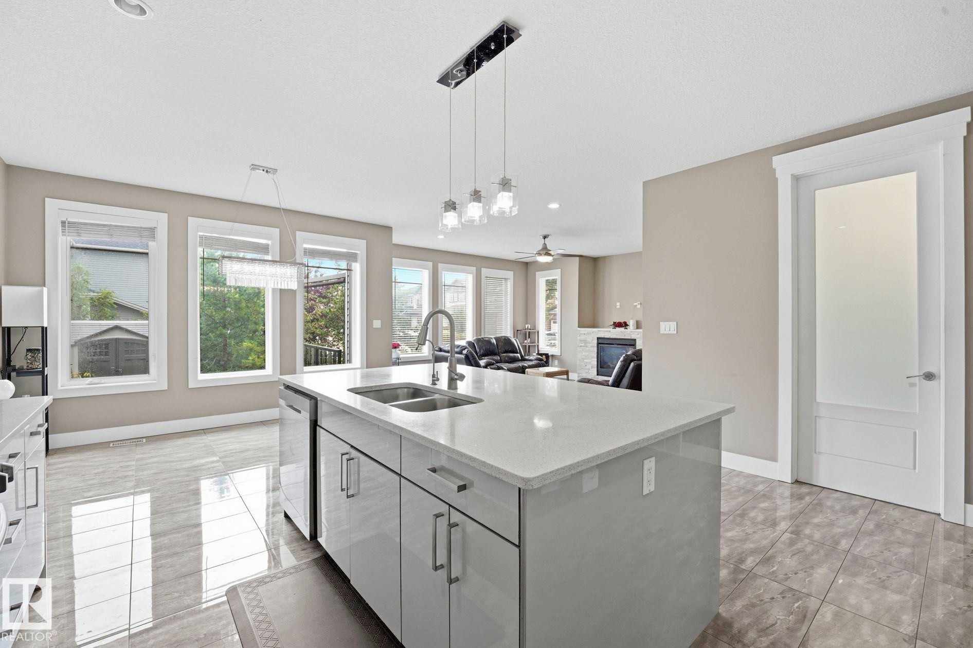 Modern kitchen island featuring a double-basin sink and integrated dishwasher - 1051 174 Street Sw, Edmonton, AB - Indoor Photo Showing Kitchen With Double Sink