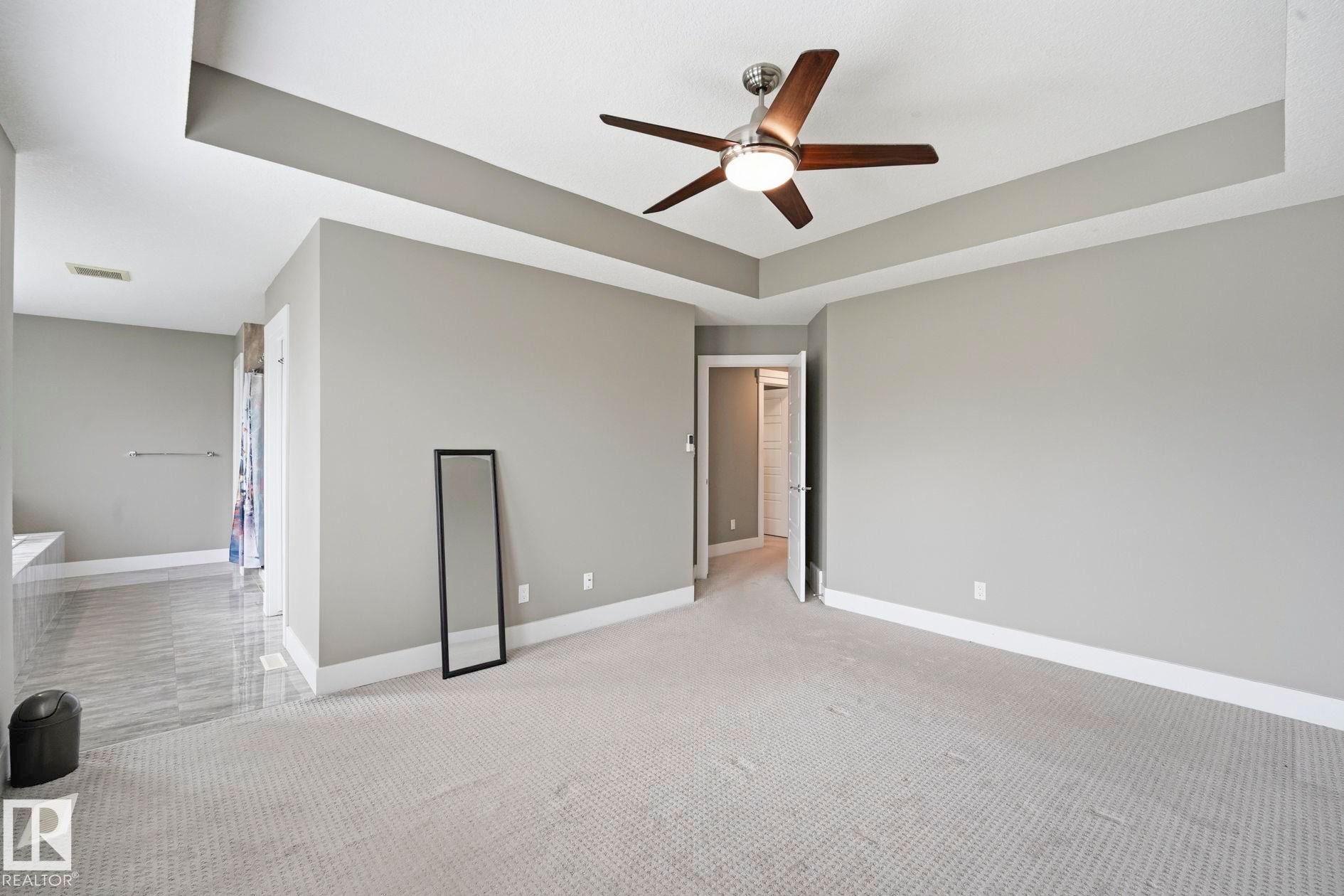 Spacious room featuring a tray ceiling with a ceiling fan, light gray wall paint, and white baseboards - 1051 174 Street Sw, Edmonton, AB - Indoor Photo Showing Other Room