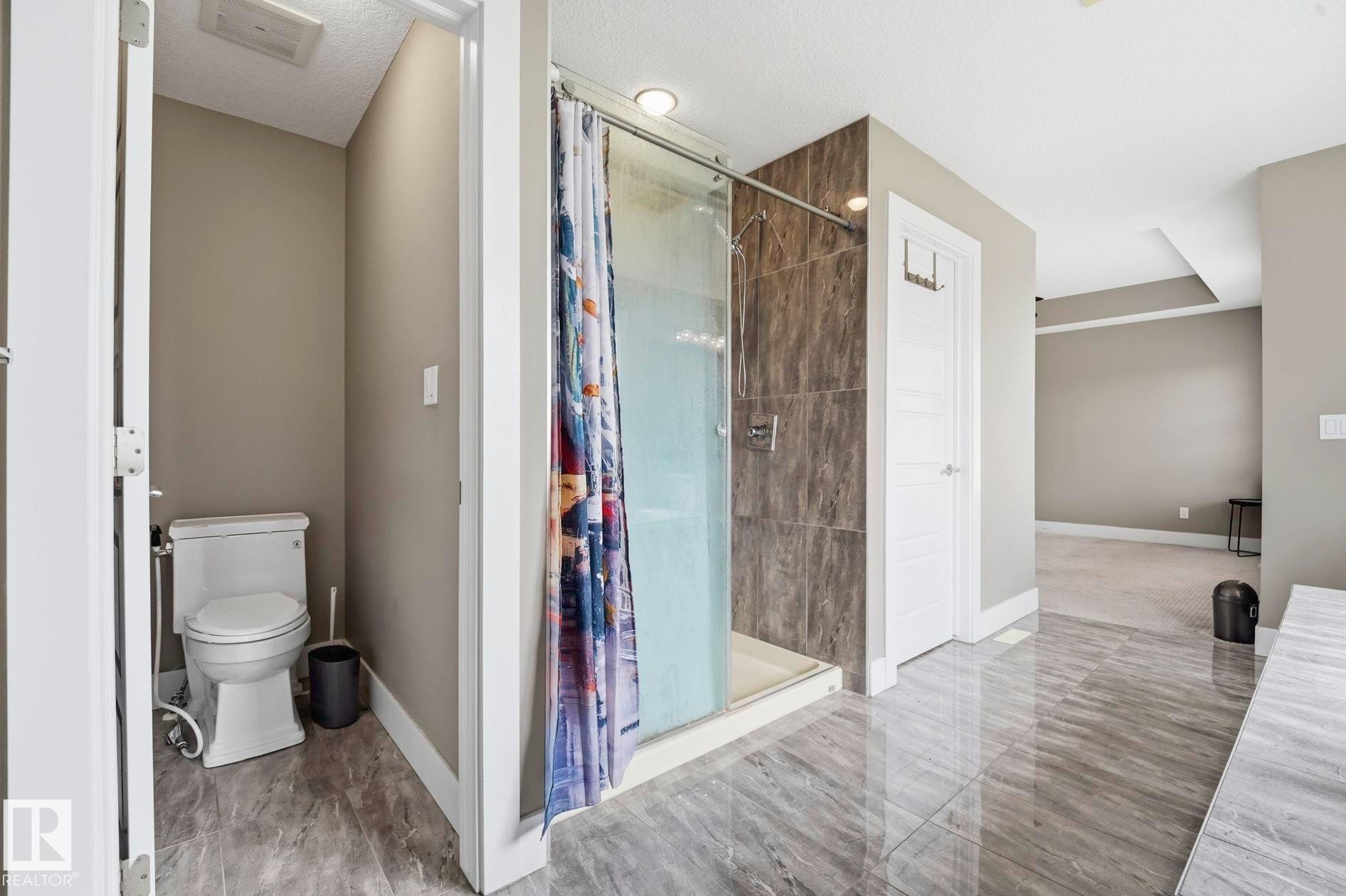 Tiled shower enclosure with glass surround and a separate commode area - 1051 174 Street Sw, Edmonton, AB - Indoor Photo Showing Bathroom