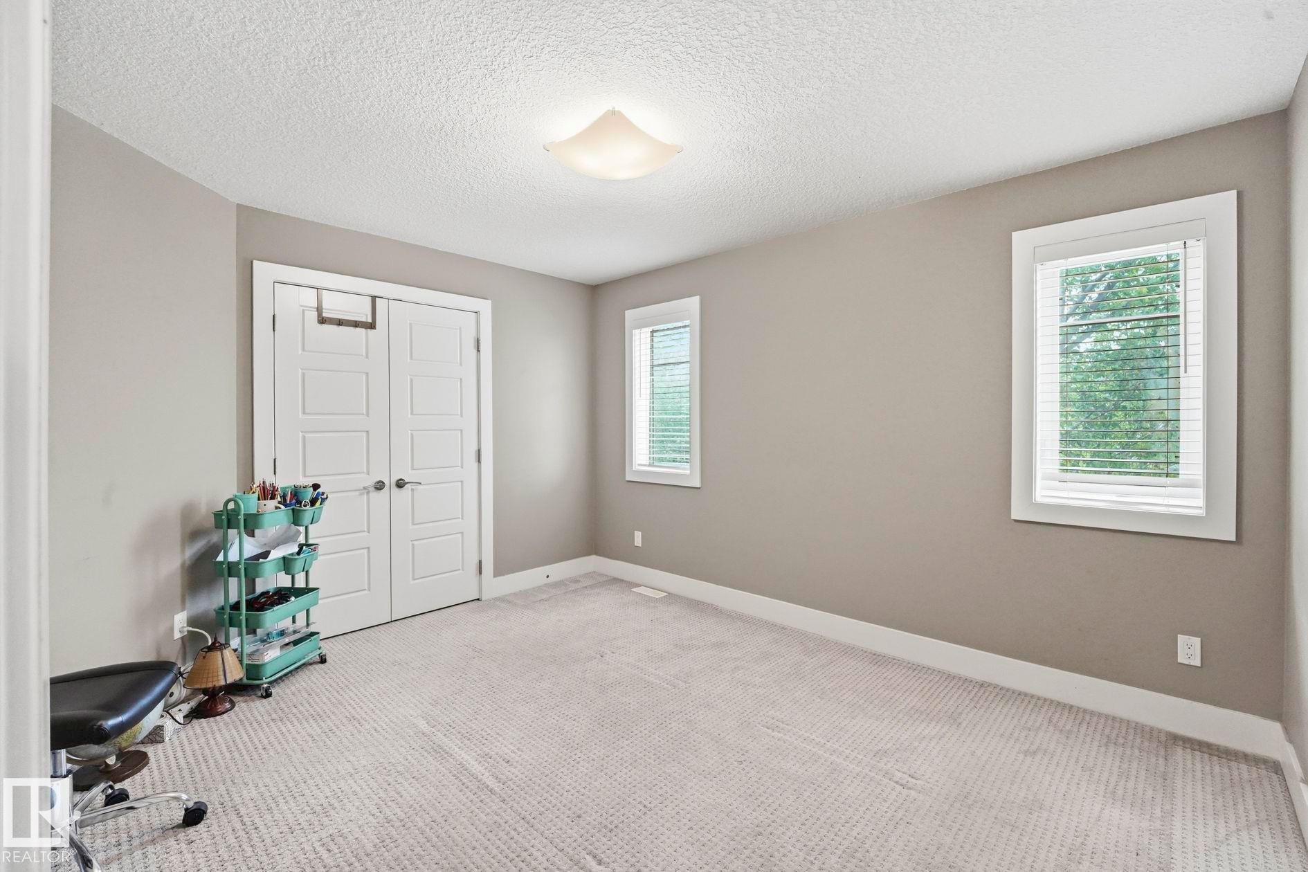 Carpeted room featuring neutral-toned walls, white trim, and two windows providing natural light - 1051 174 Street Sw, Edmonton, AB - Indoor