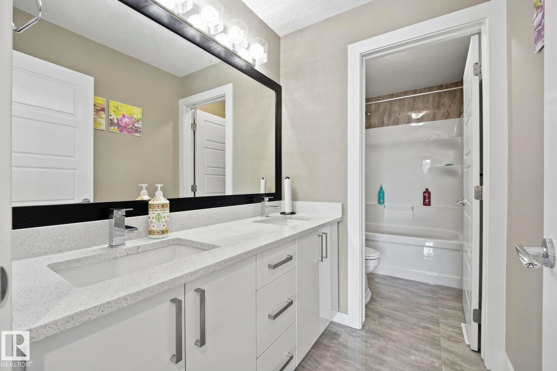 Double vanity featuring integrated sinks, light-toned countertops, and chrome fixtures - 1051 174 Street Sw, Edmonton, AB - Indoor Photo Showing Bathroom