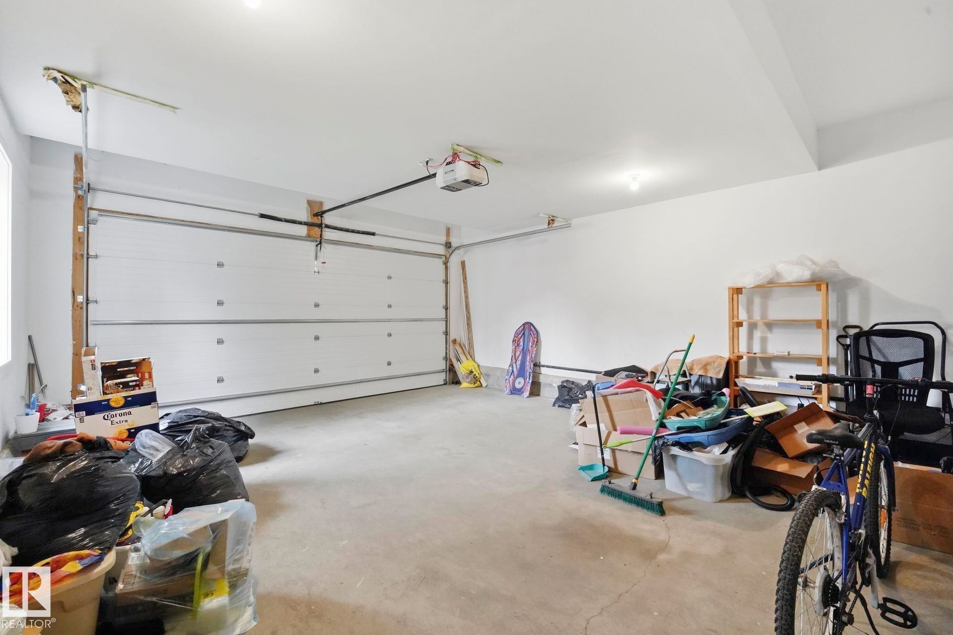 Attached garage with a white sectional door, an automatic opener, concrete flooring, and recessed lighting - 1051 174 Street Sw, Edmonton, AB - Indoor Photo Showing Garage