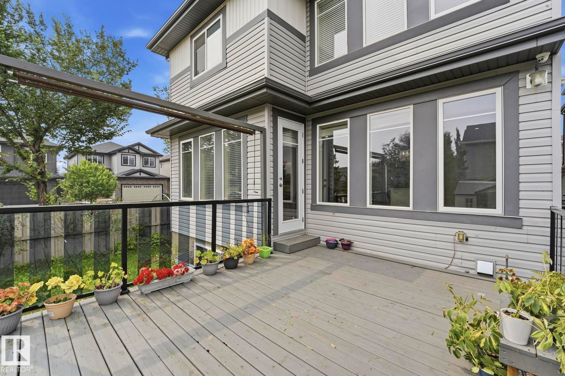 Spacious exterior deck with wood-finish flooring and glass panel railing - 1051 174 Street Sw, Edmonton, AB - Outdoor