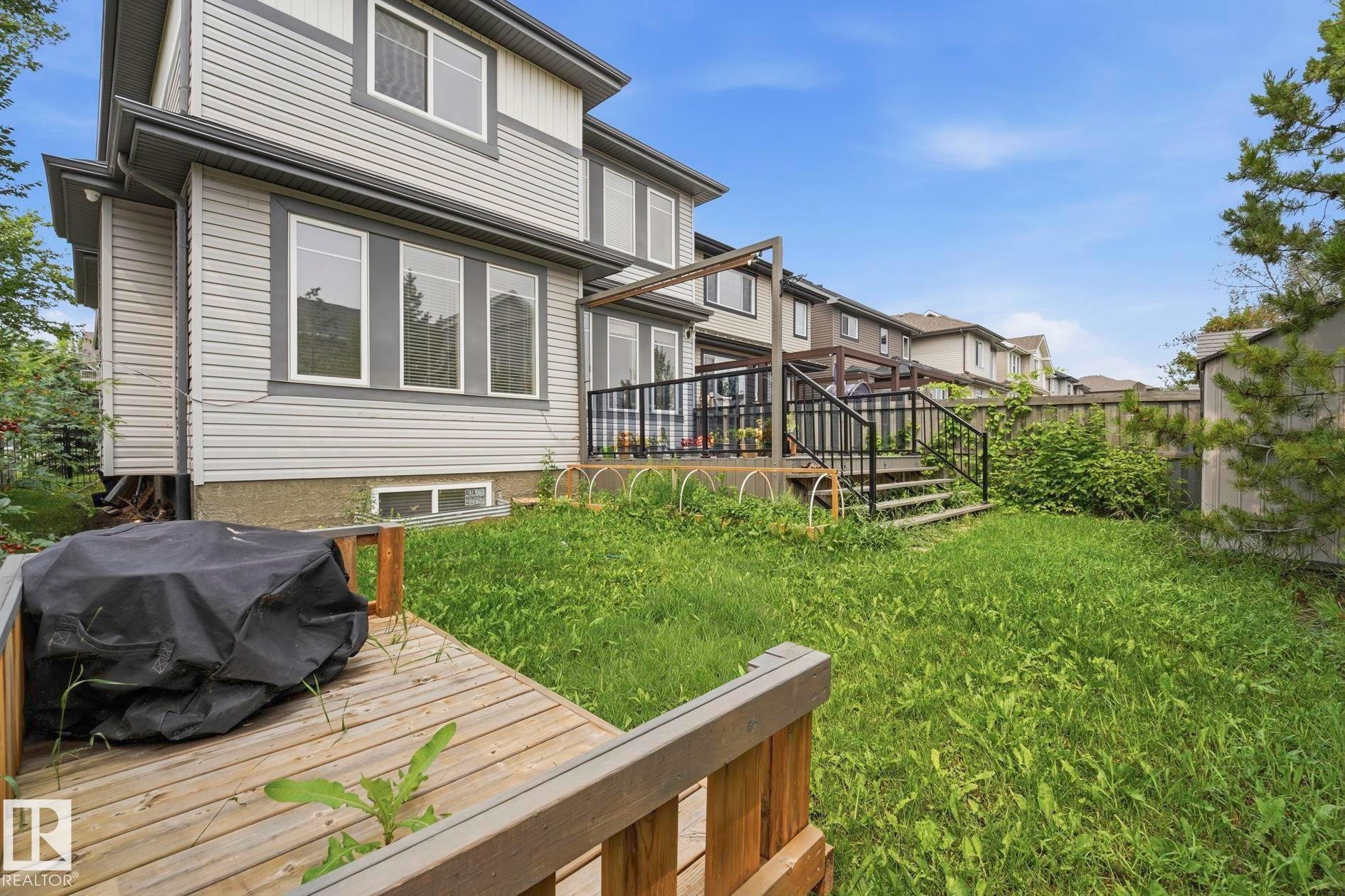 Expansive backyard featuring a wood deck with black metal railings, a pergola structure, a storage shed, and a privacy fence - 1051 174 Street Sw, Edmonton, AB - Outdoor With Deck Patio Veranda With Exterior