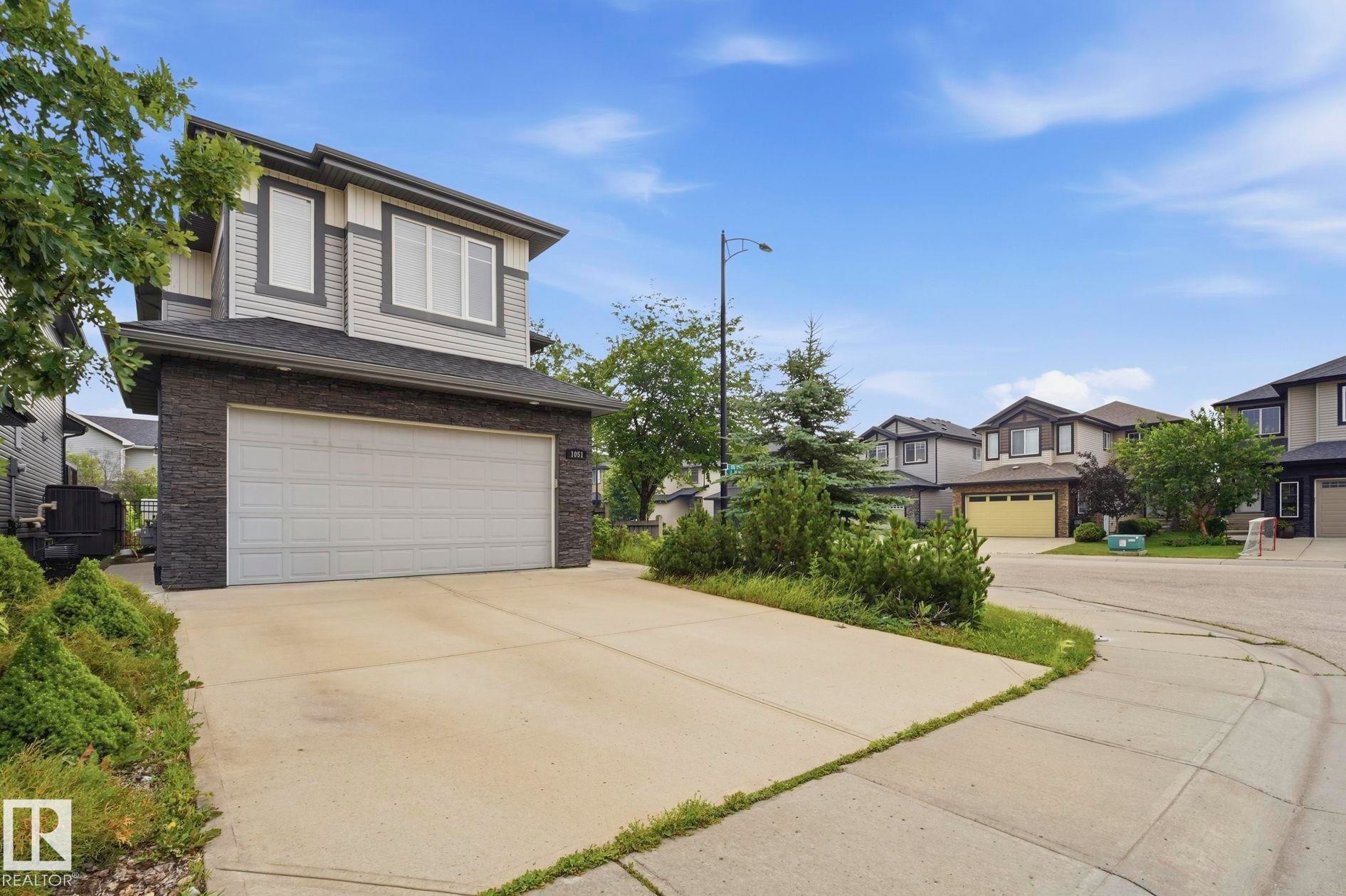 Contemporary home featuring a two-car garage, stone veneer accents, and light-toned siding - 1051 174 Street Sw, Edmonton, AB - Outdoor