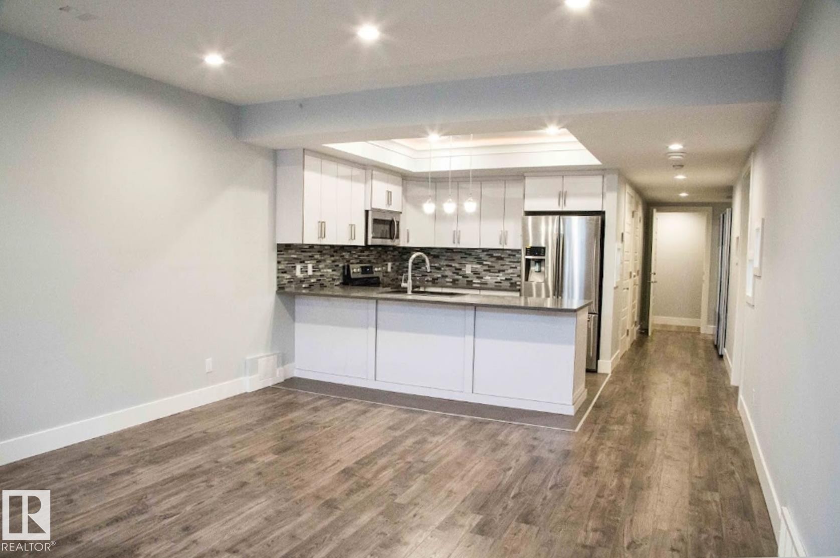 Modern kitchen featuring white cabinetry, stainless steel appliances, and a mosaic tile backsplash - 1051 174 Street Sw, Edmonton, AB - Indoor Photo Showing Kitchen With Double Sink