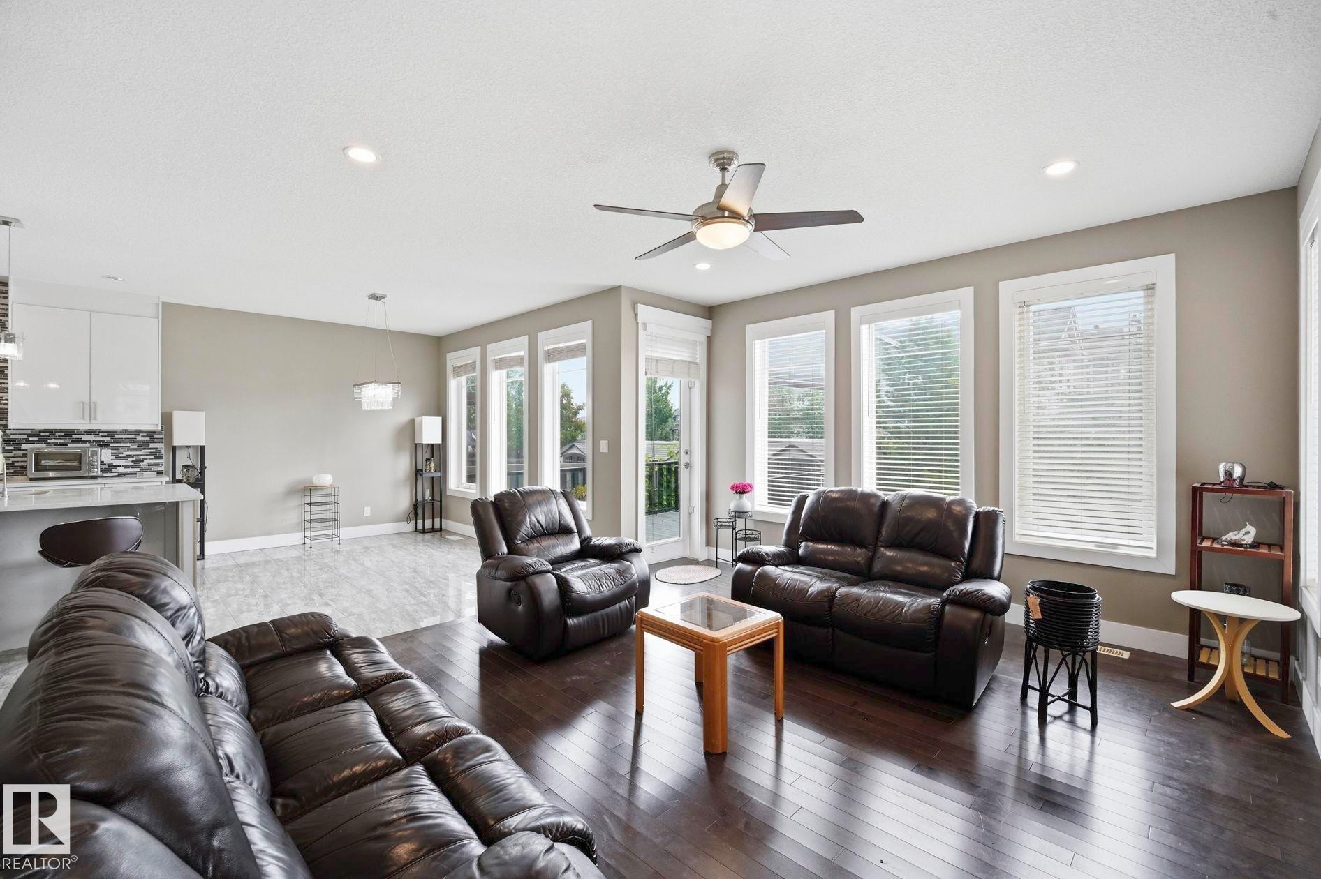 Expansive living area featuring rich wood-finish flooring, a contemporary ceiling fan, and recessed lighting - 1051 174 Street Sw, Edmonton, AB - Indoor Photo Showing Living Room