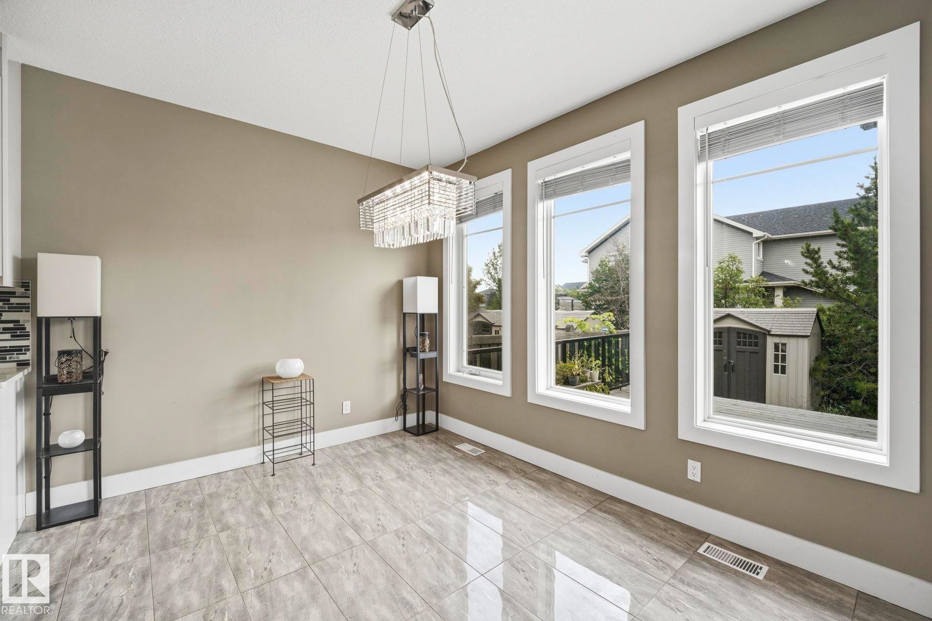 Dining area with large format tile flooring and a multi-light crystal chandelier - 1051 174 Street Sw, Edmonton, AB - Indoor Photo Showing Other Room