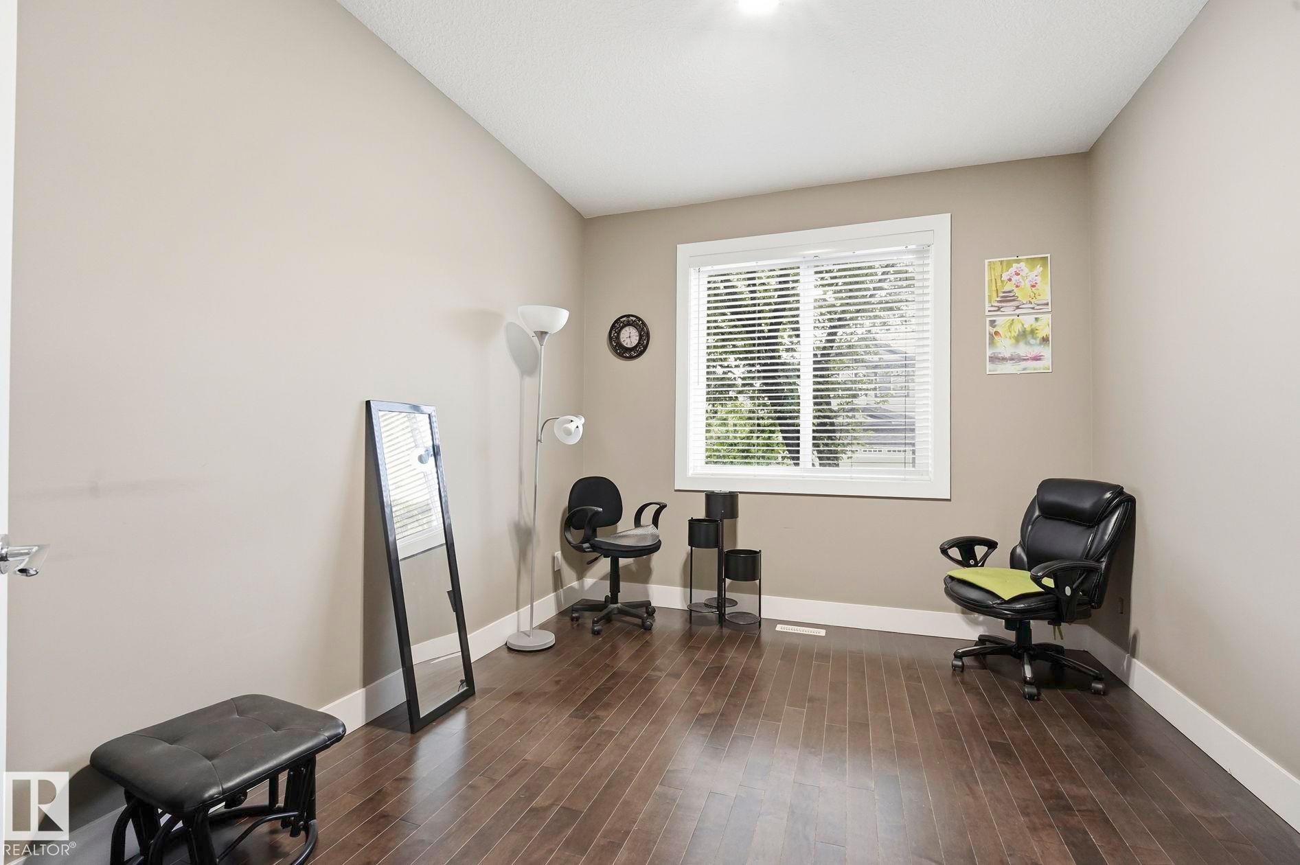 Spacious room featuring wood-finish flooring and neutral wall tones - 1051 174 Street Sw, Edmonton, AB - Indoor