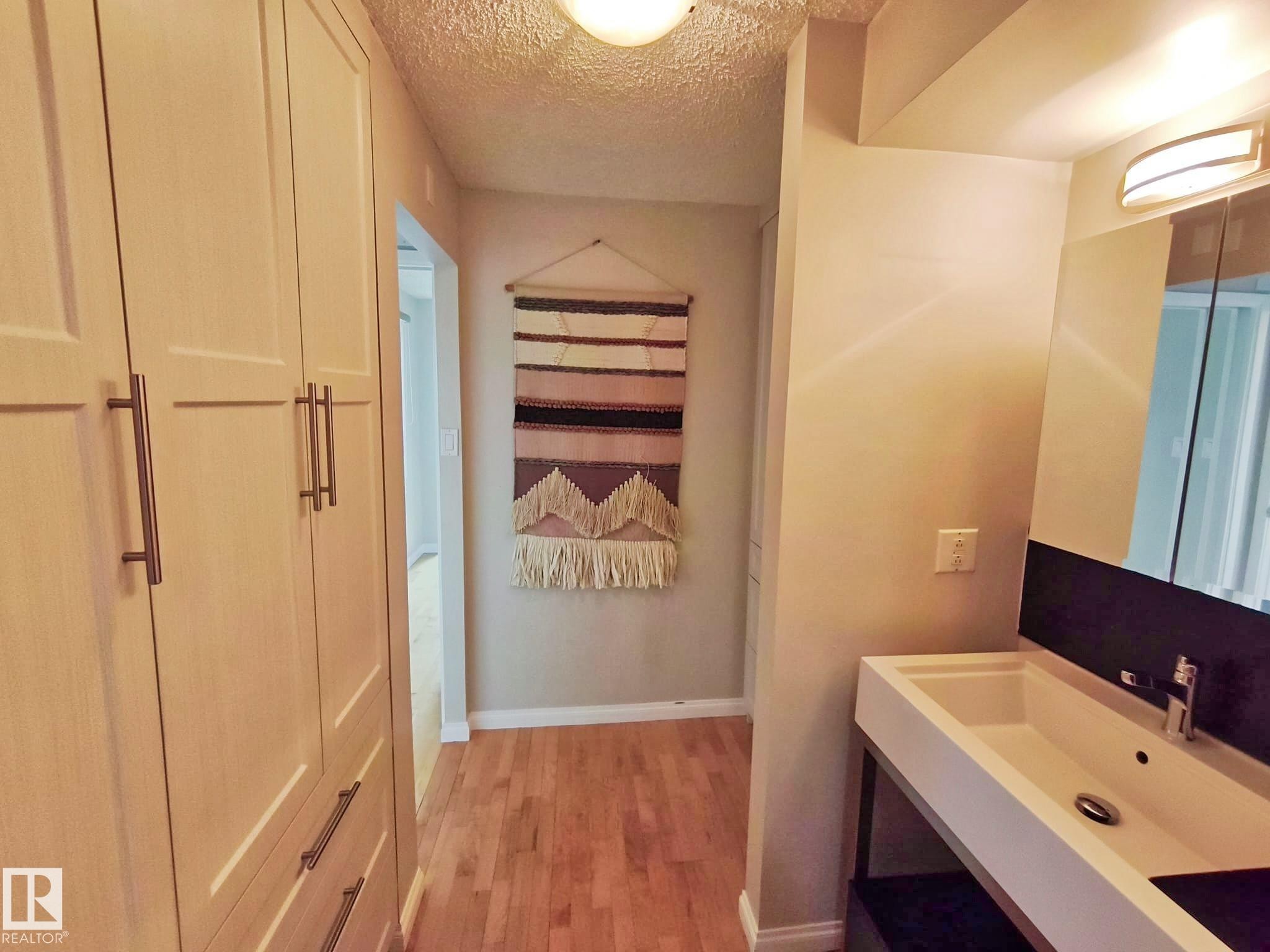 Hallway featuring light wood-finish built-in cabinetry with dark hardware - #509 10149 Saskatchewan Dr Nw, Edmonton, AB - Indoor Photo Showing Bathroom