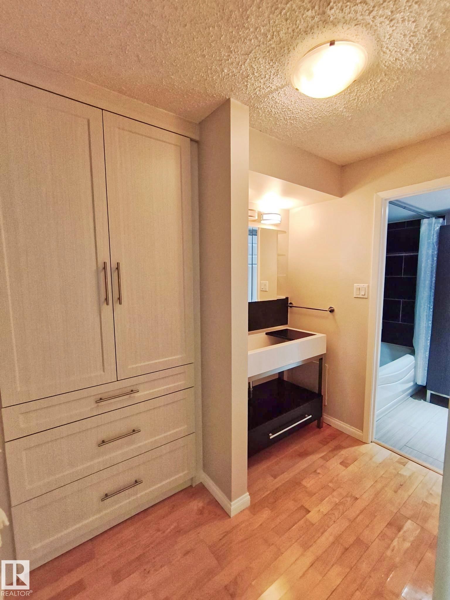Light wood-finish flooring extending from a built-in wardrobe with brushed nickel hardware - #509 10149 Saskatchewan Dr Nw, Edmonton, AB - Indoor Photo Showing Other Room