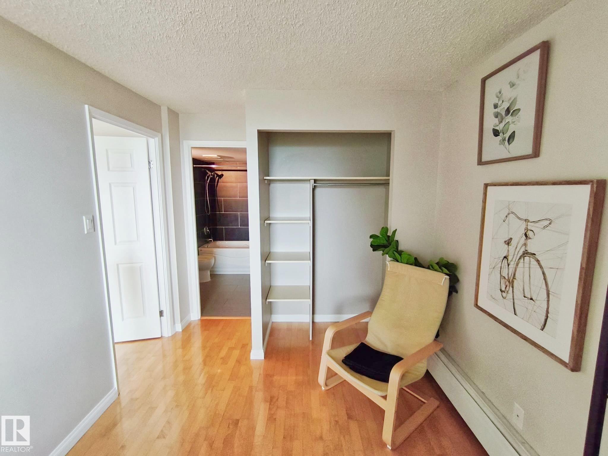 Hardwood flooring throughout featuring an open closet with shelving and a hanging rod - #509 10149 Saskatchewan Dr Nw, Edmonton, AB - Indoor Photo Showing Other Room