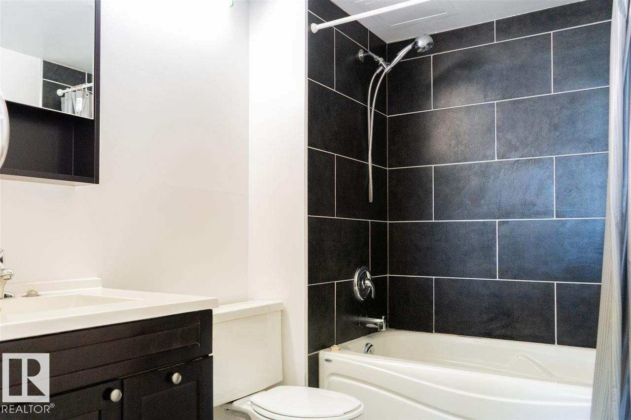 Bathroom featuring a dark wood-finish vanity with a white countertop and an integrated sink - #509 10149 Saskatchewan Dr Nw, Edmonton, AB - Indoor Photo Showing Bathroom