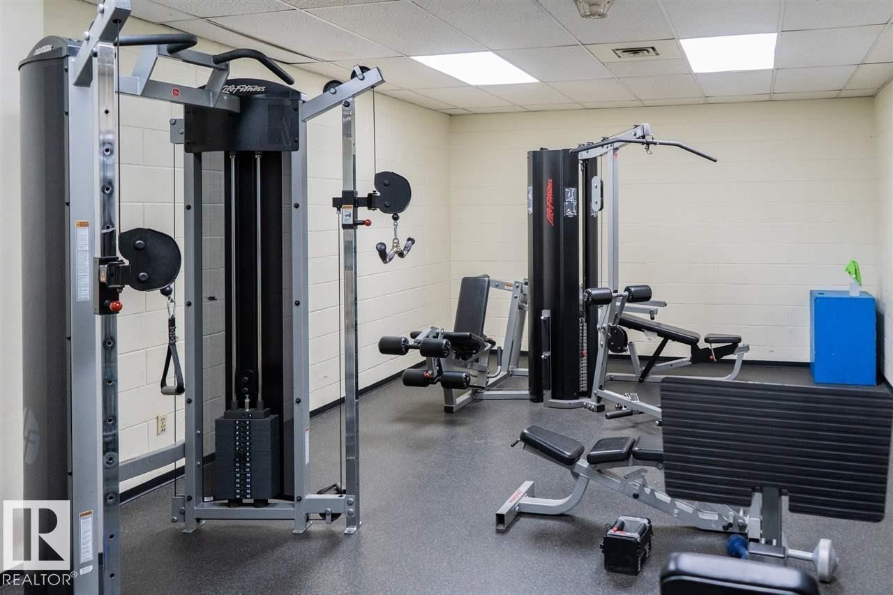 Fitness center featuring multiple exercise machines, durable rubber flooring, and bright overhead lighting - #509 10149 Saskatchewan Dr Nw, Edmonton, AB - Indoor Photo Showing Gym Room