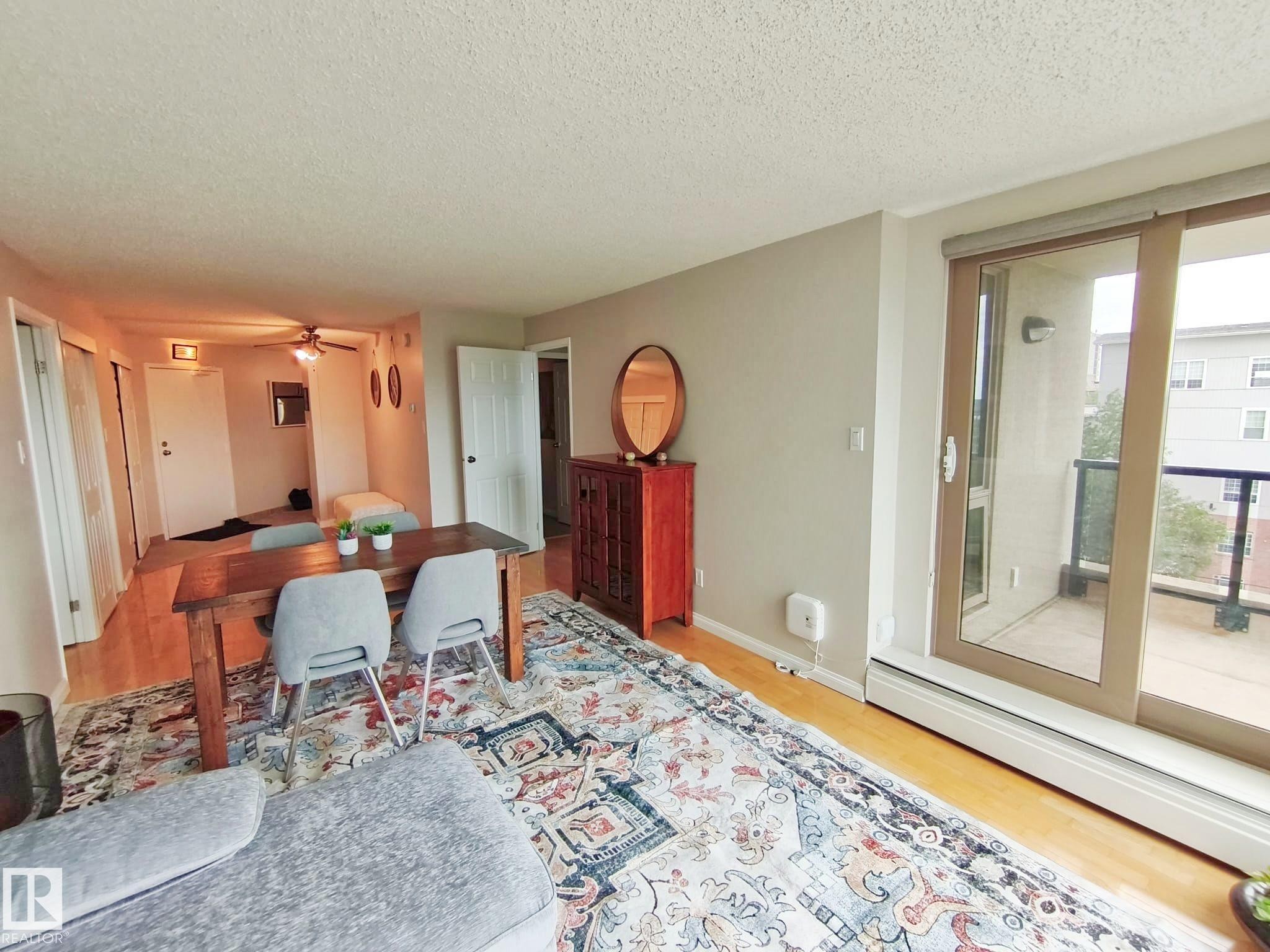 Open-concept living area with wood-finish flooring, a large area rug, and neutral wall tones - #509 10149 Saskatchewan Dr Nw, Edmonton, AB - Indoor Photo Showing Other Room
